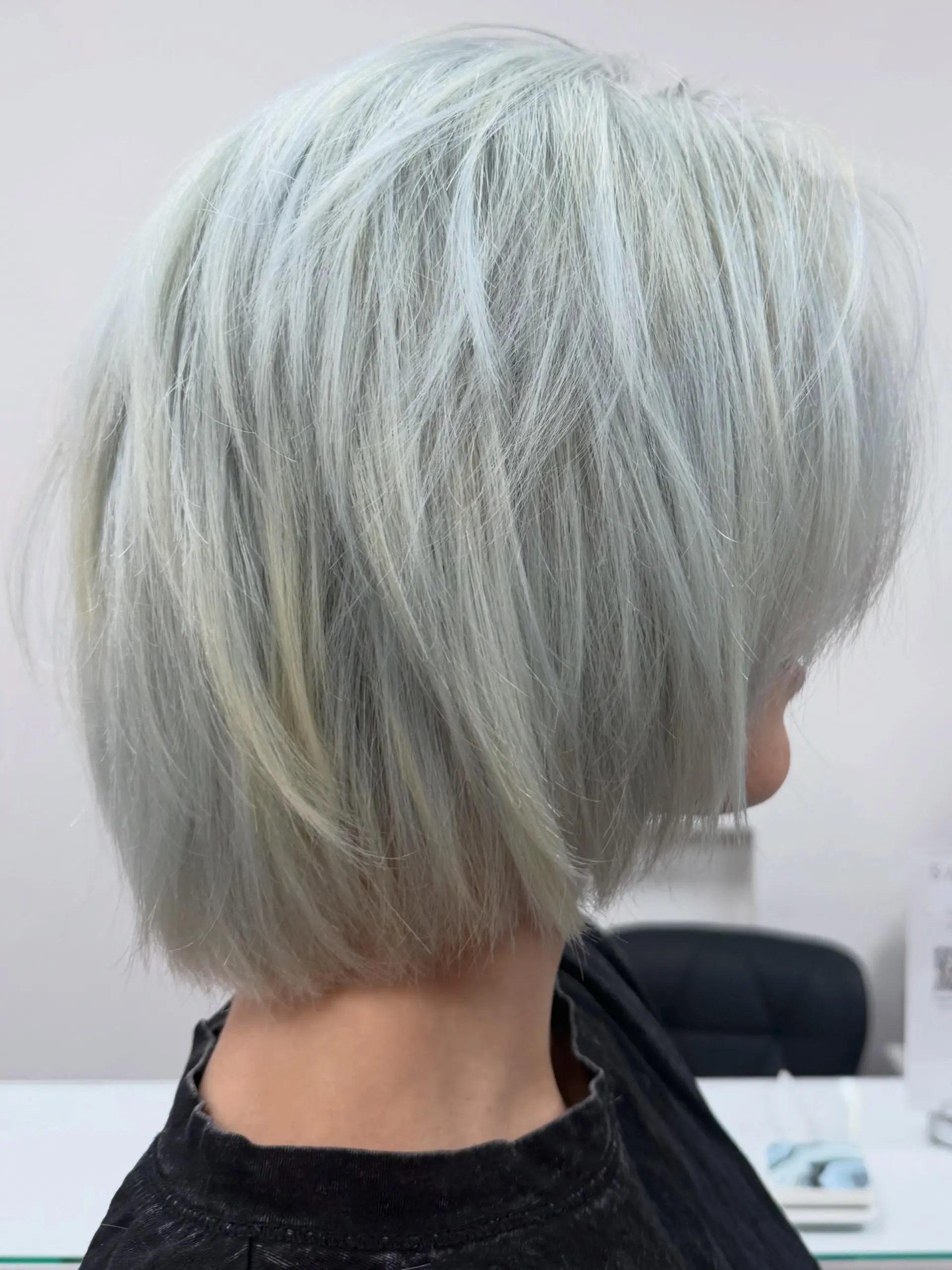 A textured chin-length bob colored in an icy blue-steel platinum blonde with shattered, piecey layers. 1