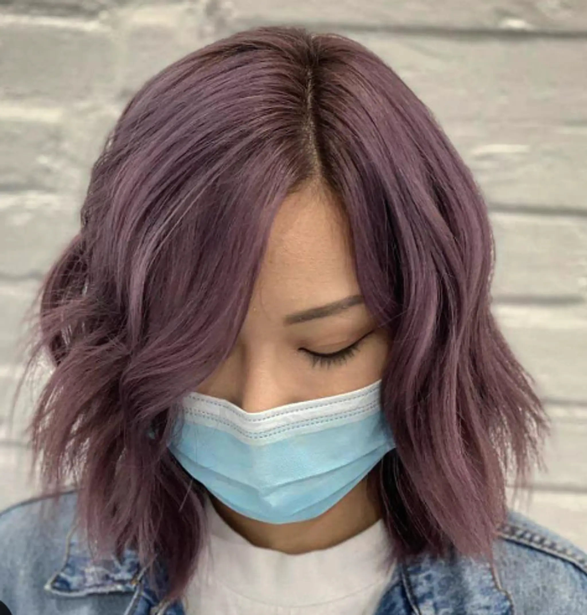 Medium-length wavy hair in a lilac shade with a middle part and textured layers.