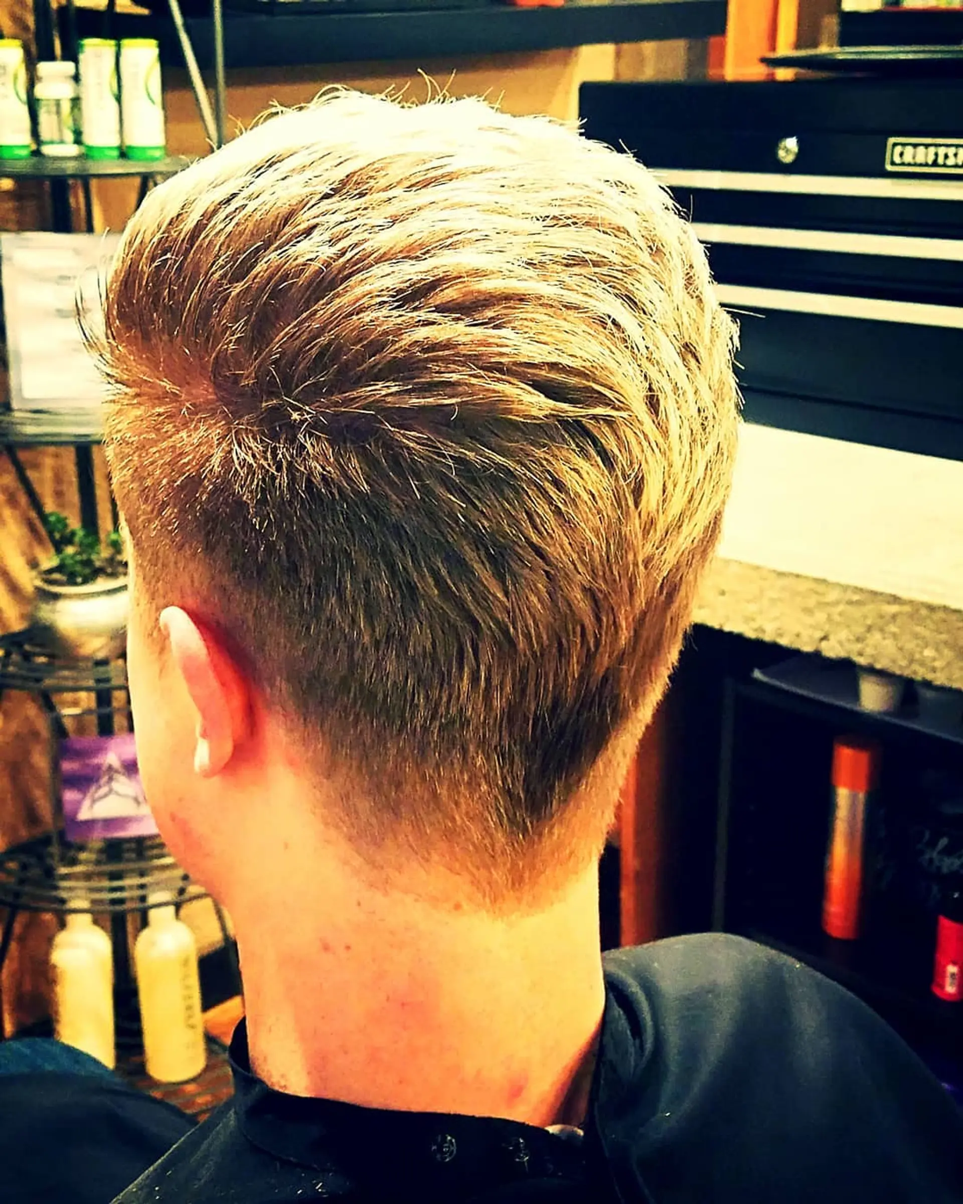 A tapered short haircut featuring a cleanly blended neckline and textured styling throughout the crown. 1