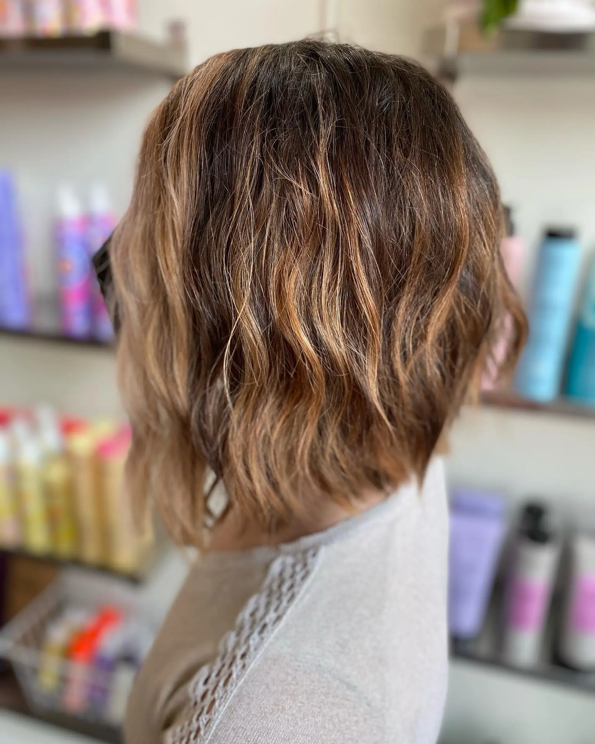 Textured chin-length bob styled with effortless, lived-in waves and warm bronde balayage highlights. 1