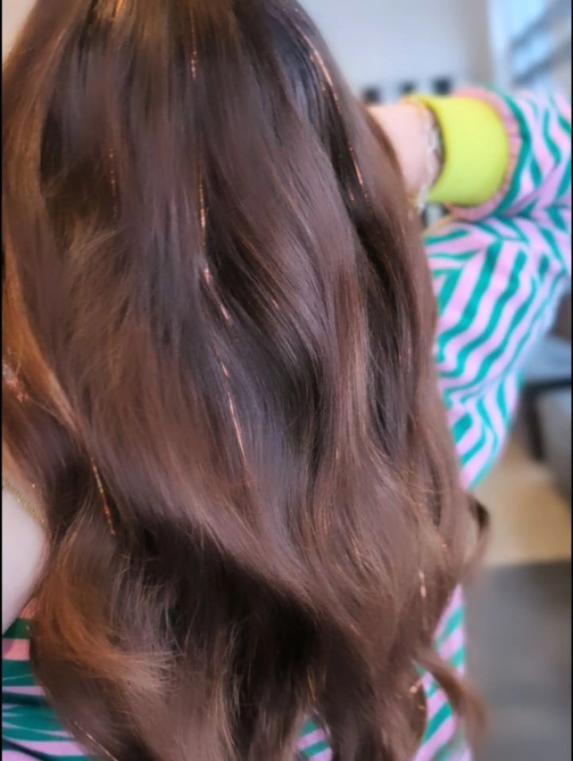 Medium-length wavy brunette hair accented with delicate, shimmering hair tinsel strands. 1