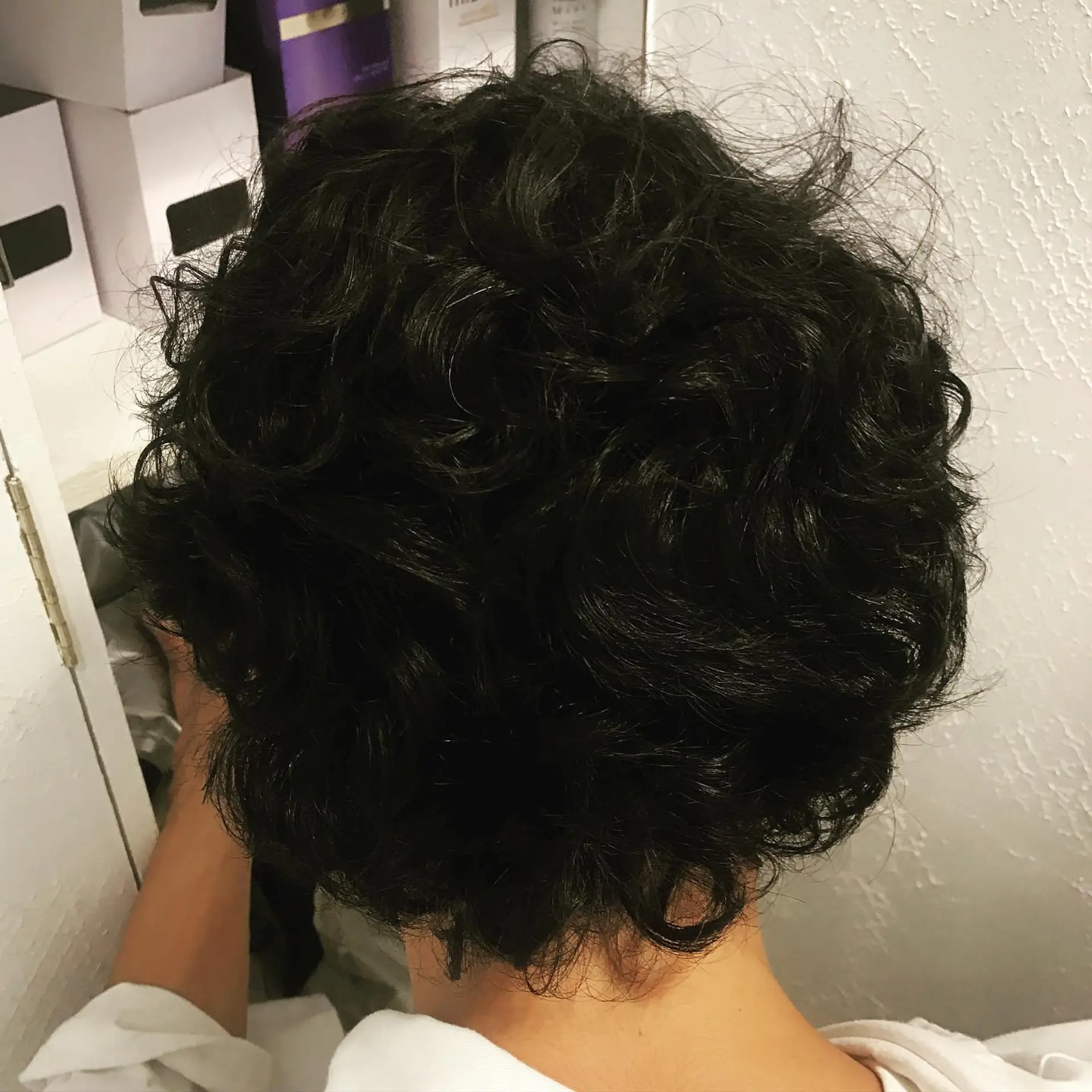 A short voluminous hairstyle featuring full, defined curls and soft texture throughout. 1
