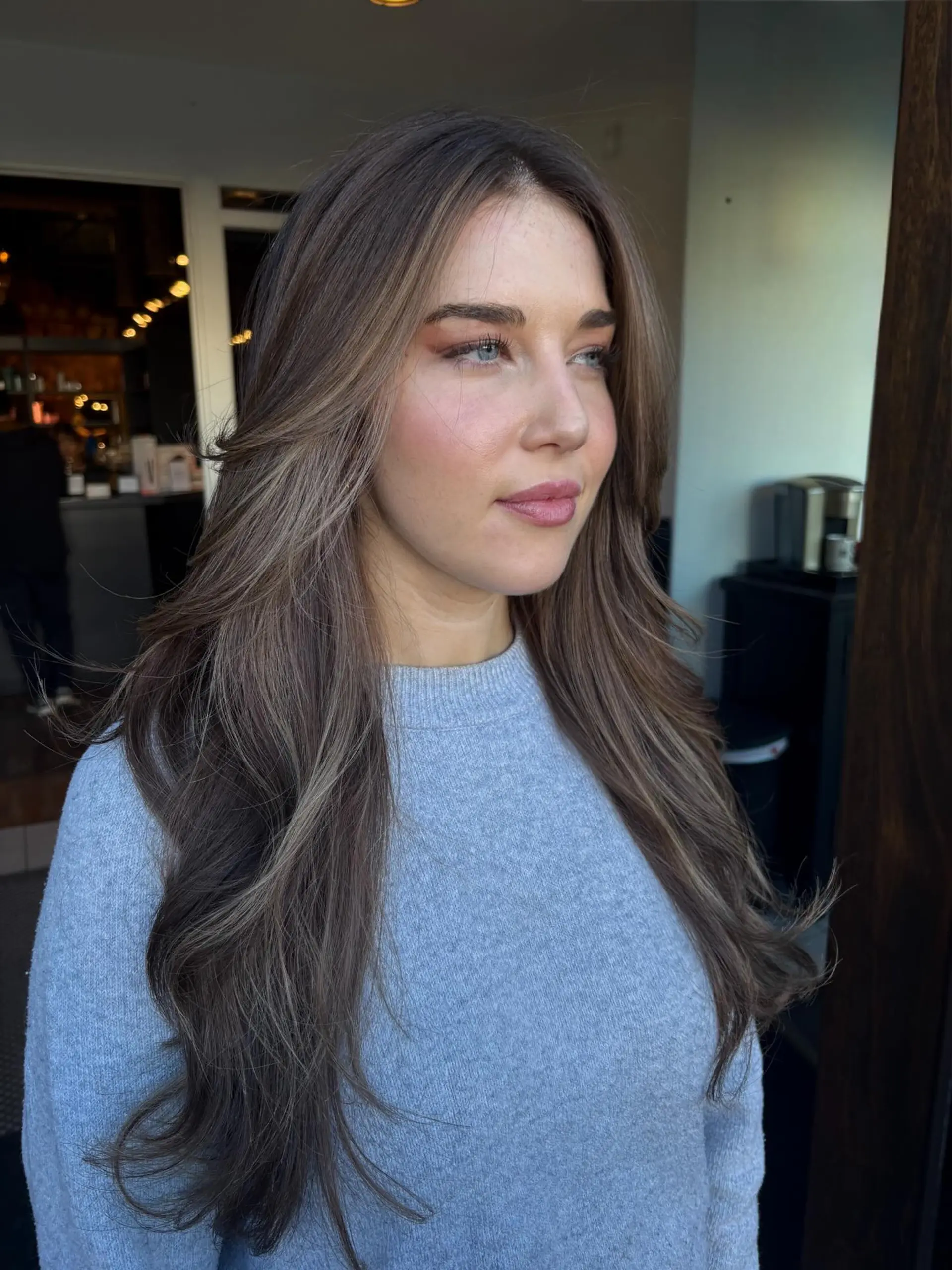 Long ash-brunette hair with soft, face-framing layers and subtle dimensional blonde highlights styled in loose waves. 1