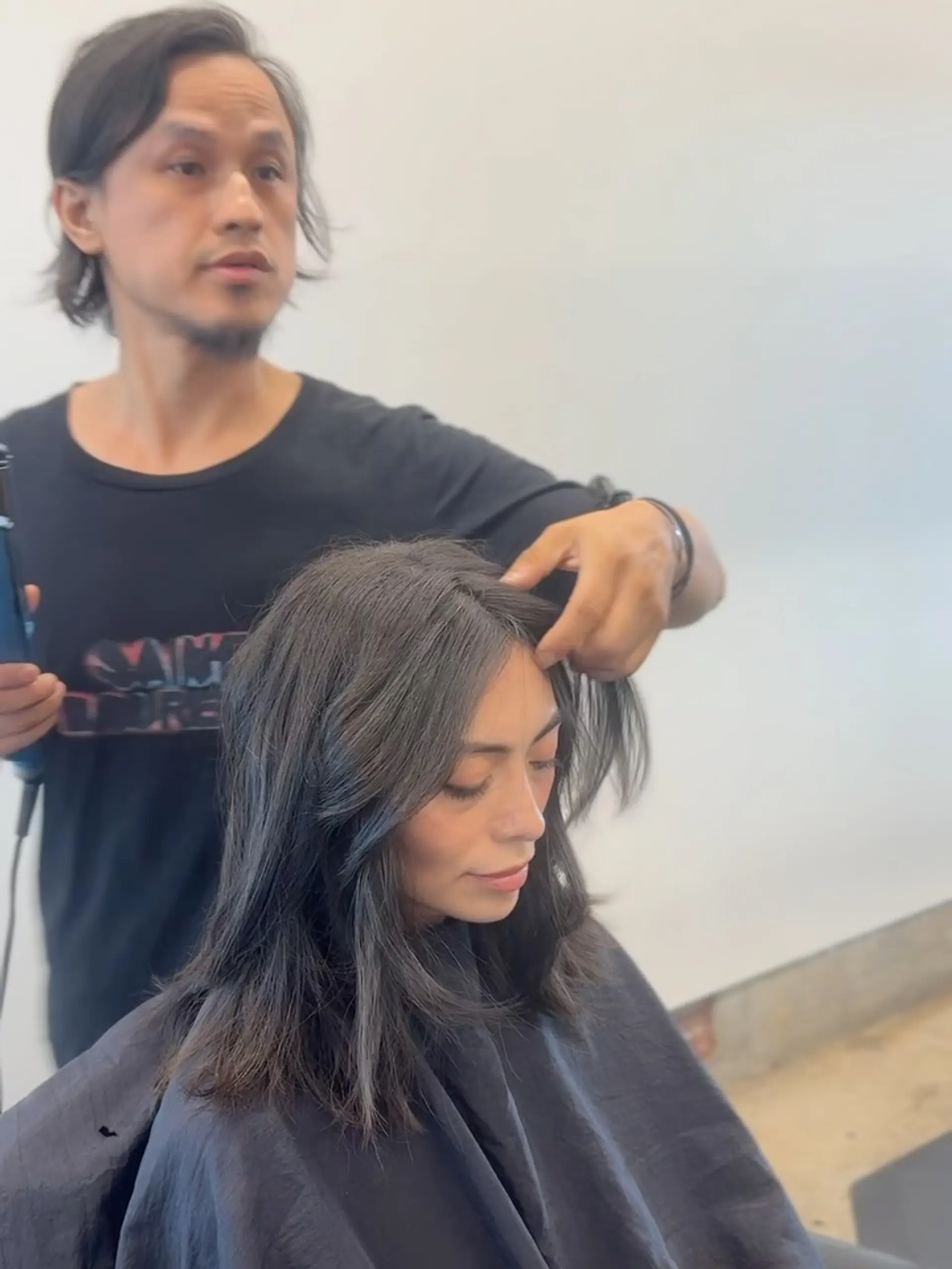 Medium-length dark layered haircut styled with face-framing curtain bangs. 1