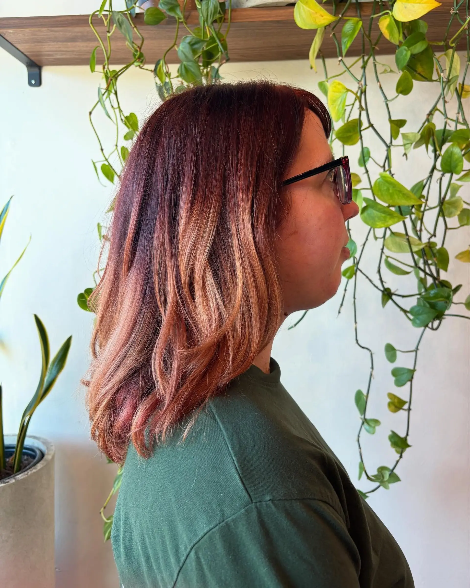 Medium-length style featuring deep auburn and rich copper roots blending into soft, warm golden tones with gentle waves. 1