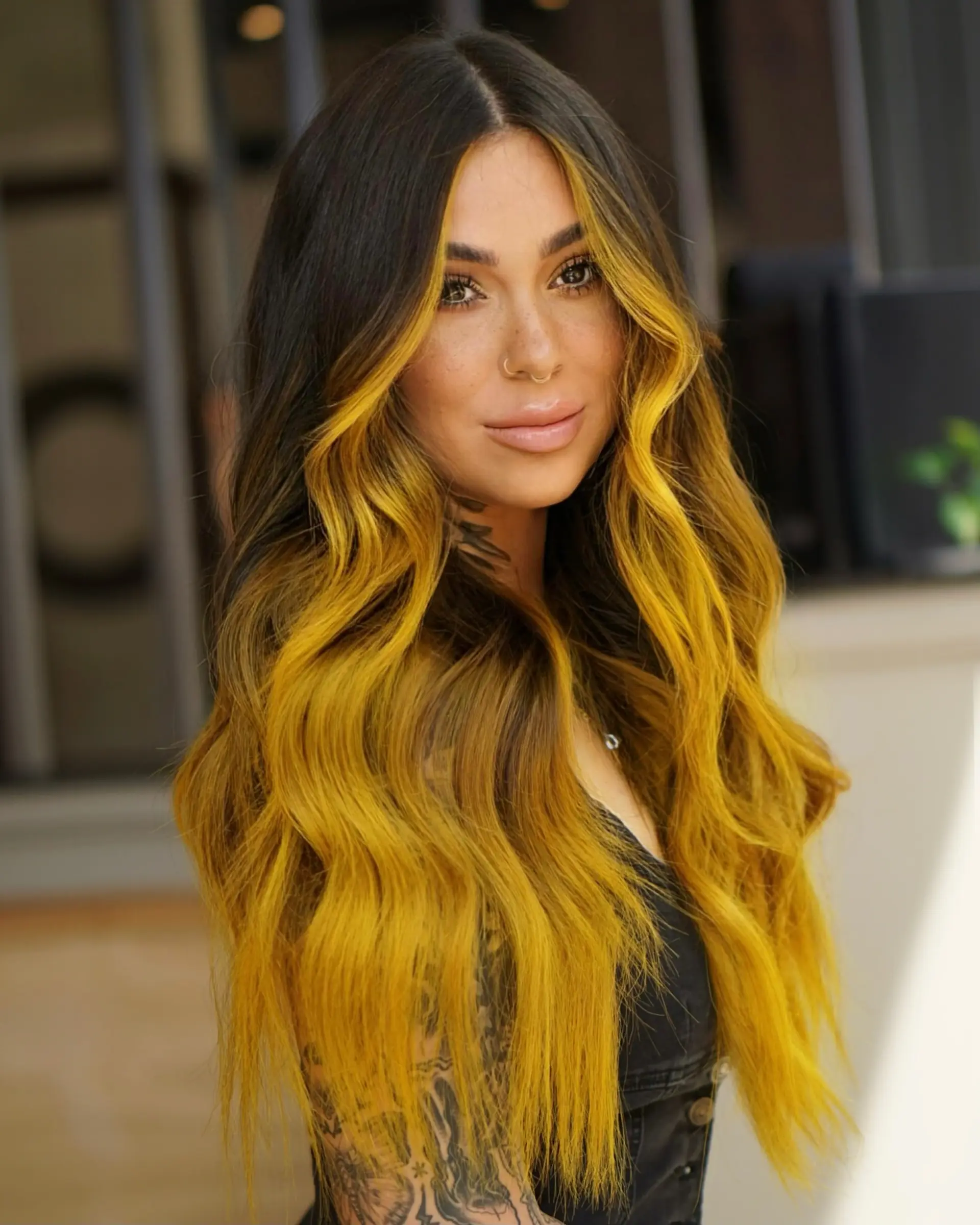 Long wavy dark hair transformed with high-contrast, dandelion-yellow balayage and bold face-framing money piece highlights. 1