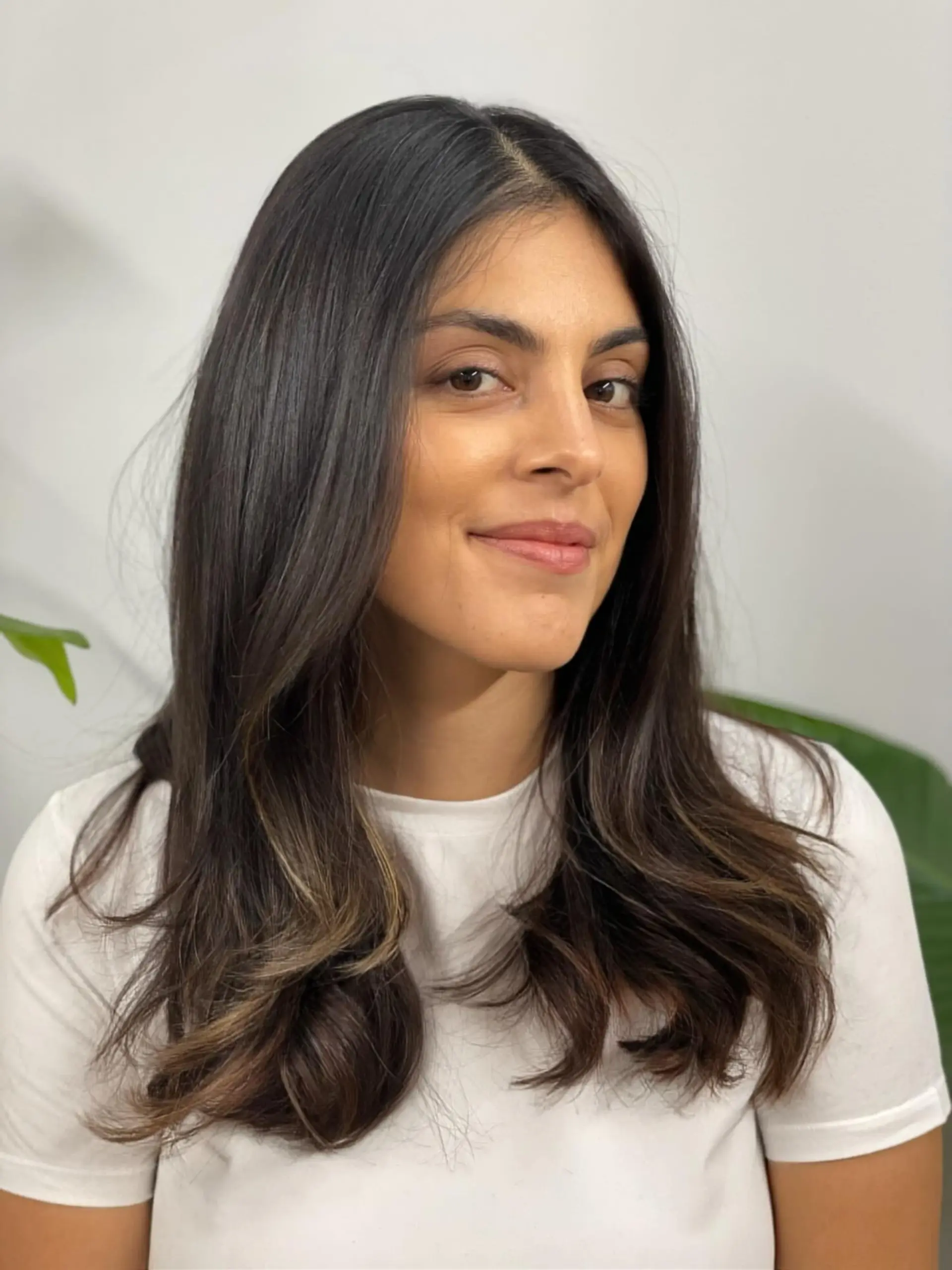 Long brunette layered haircut styled with a center part and soft, bouncy flipped ends. 1