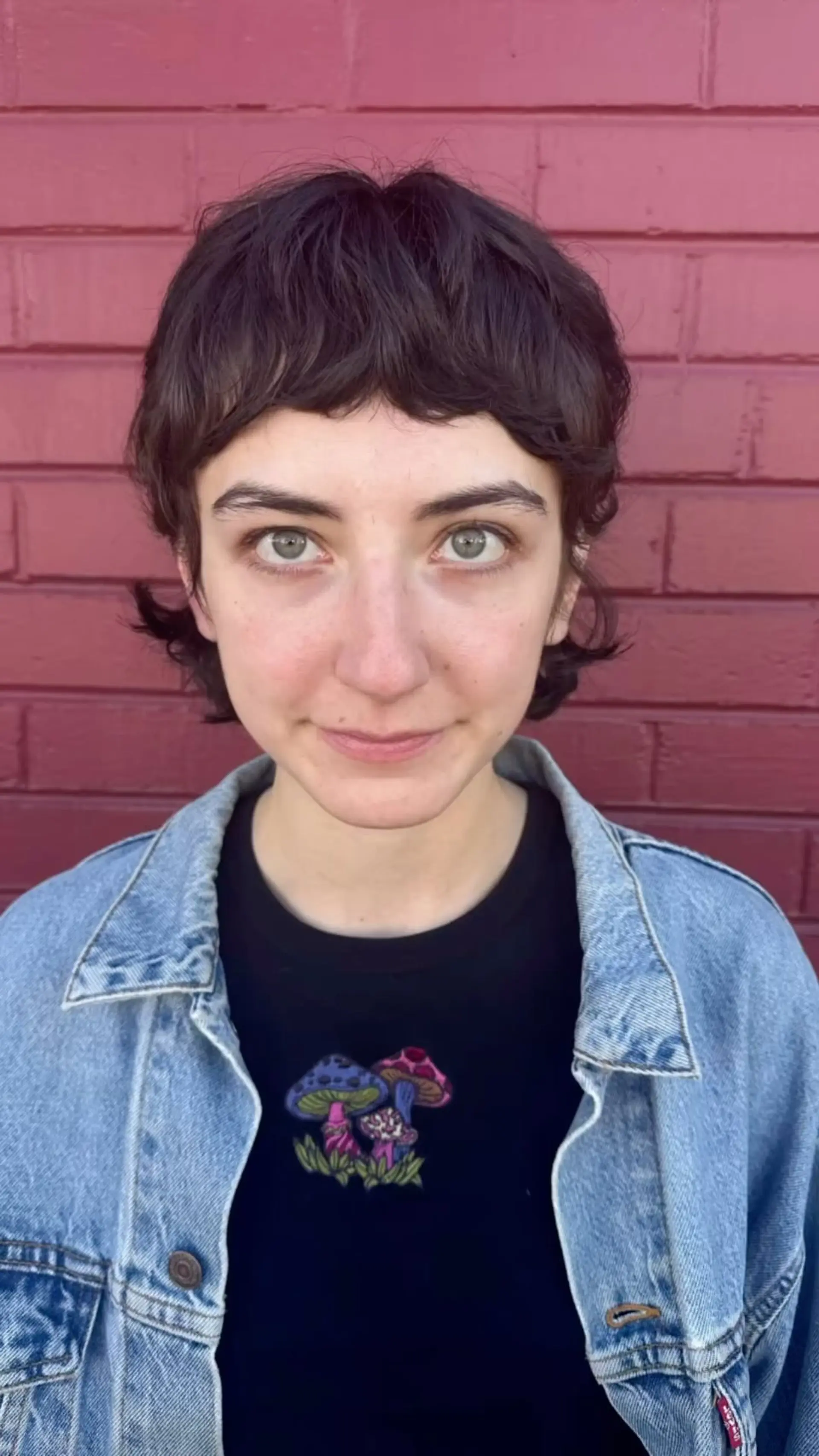 A short, textured wavy pixie mullet featuring choppy micro bangs and wispy layers around the ears and nape. 1
