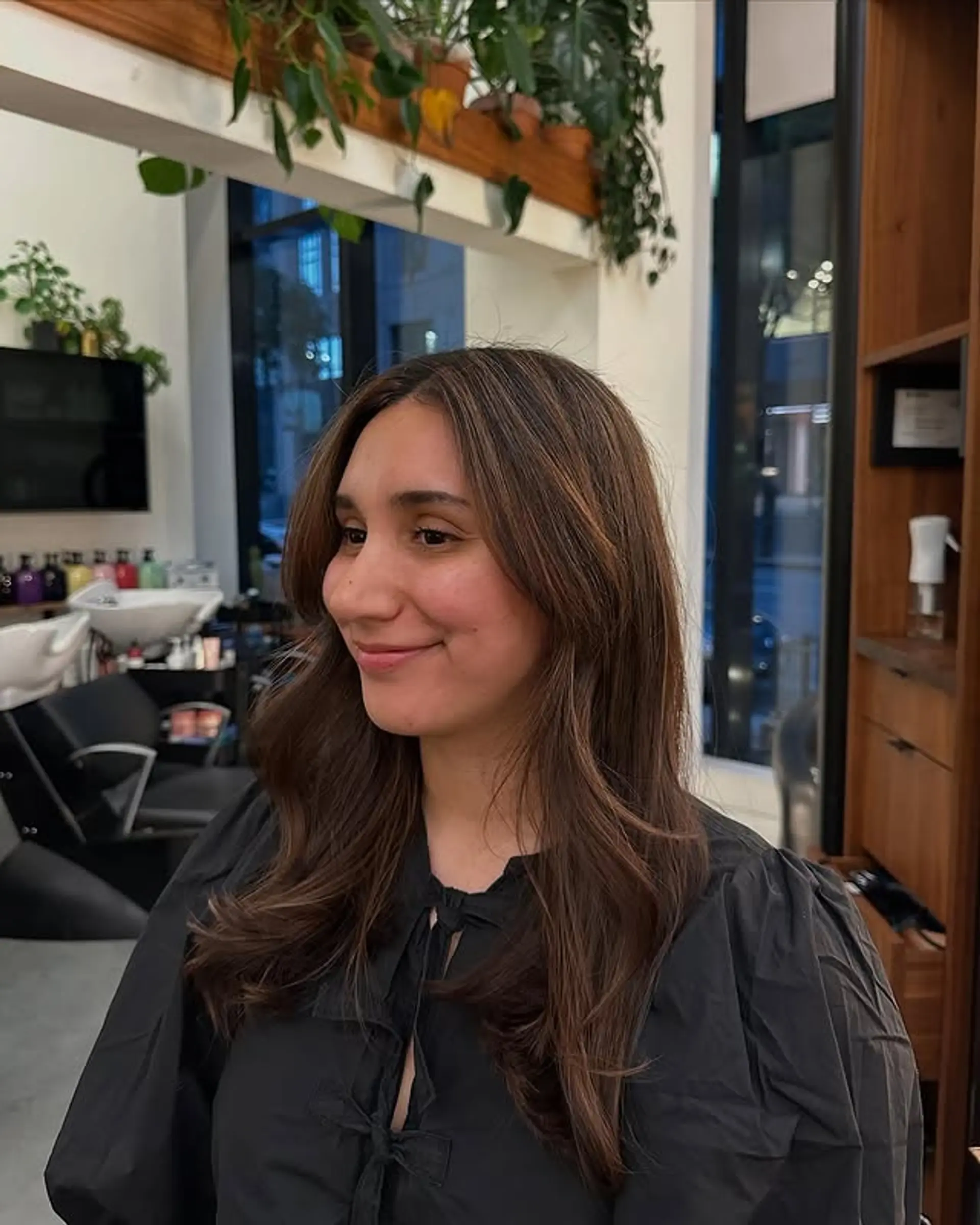 A long layered haircut with face-framing curtain bangs and a bronde color. 1