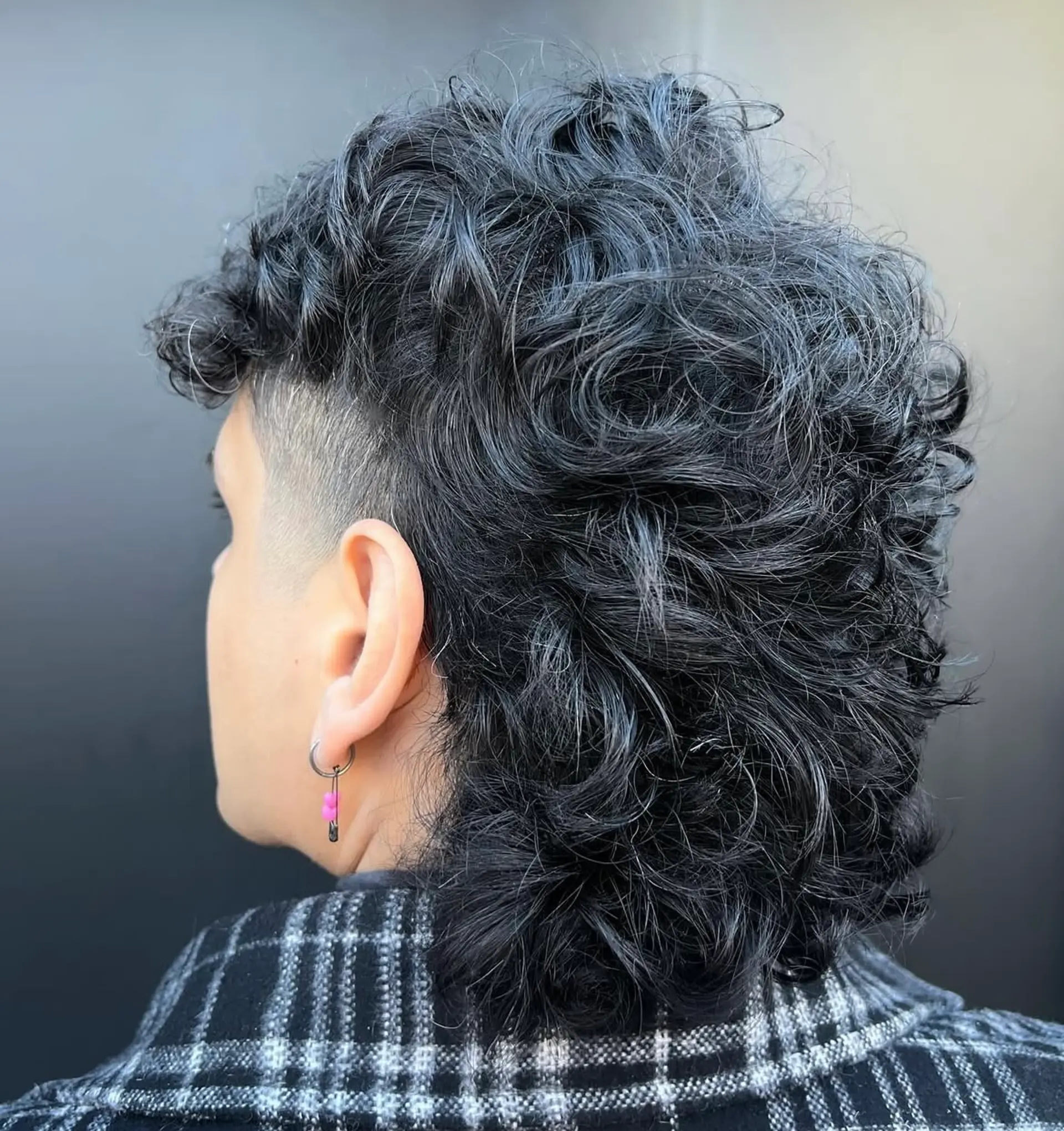 A modern shag mullet with textured, curly hair and tapered sides. 1