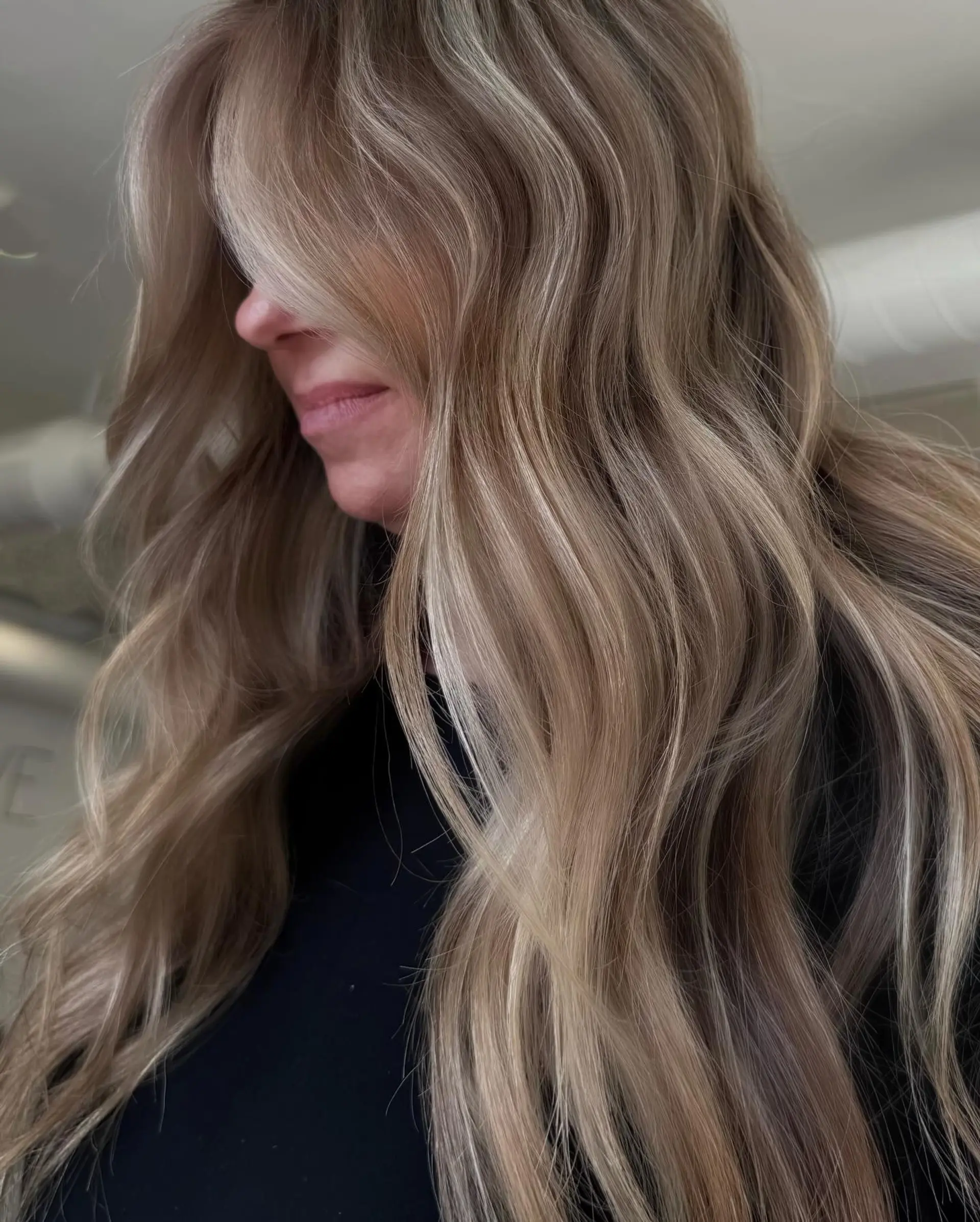 Long dimensional blonde hair styled in soft, loose waves with face-framing curtain layers. 1