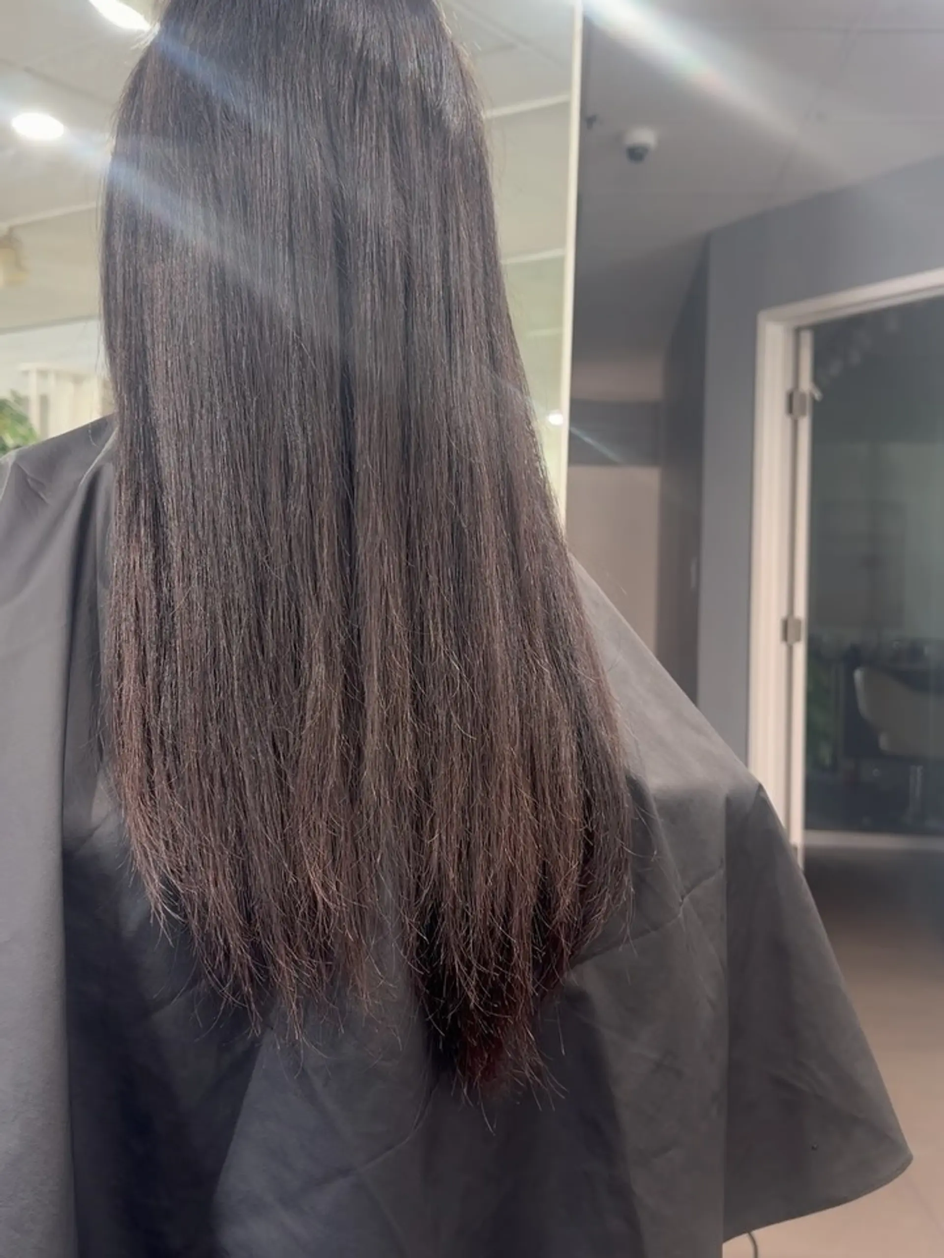 Long, dark brown hair straightened sleek and smooth, falling down past mid-back. 1
