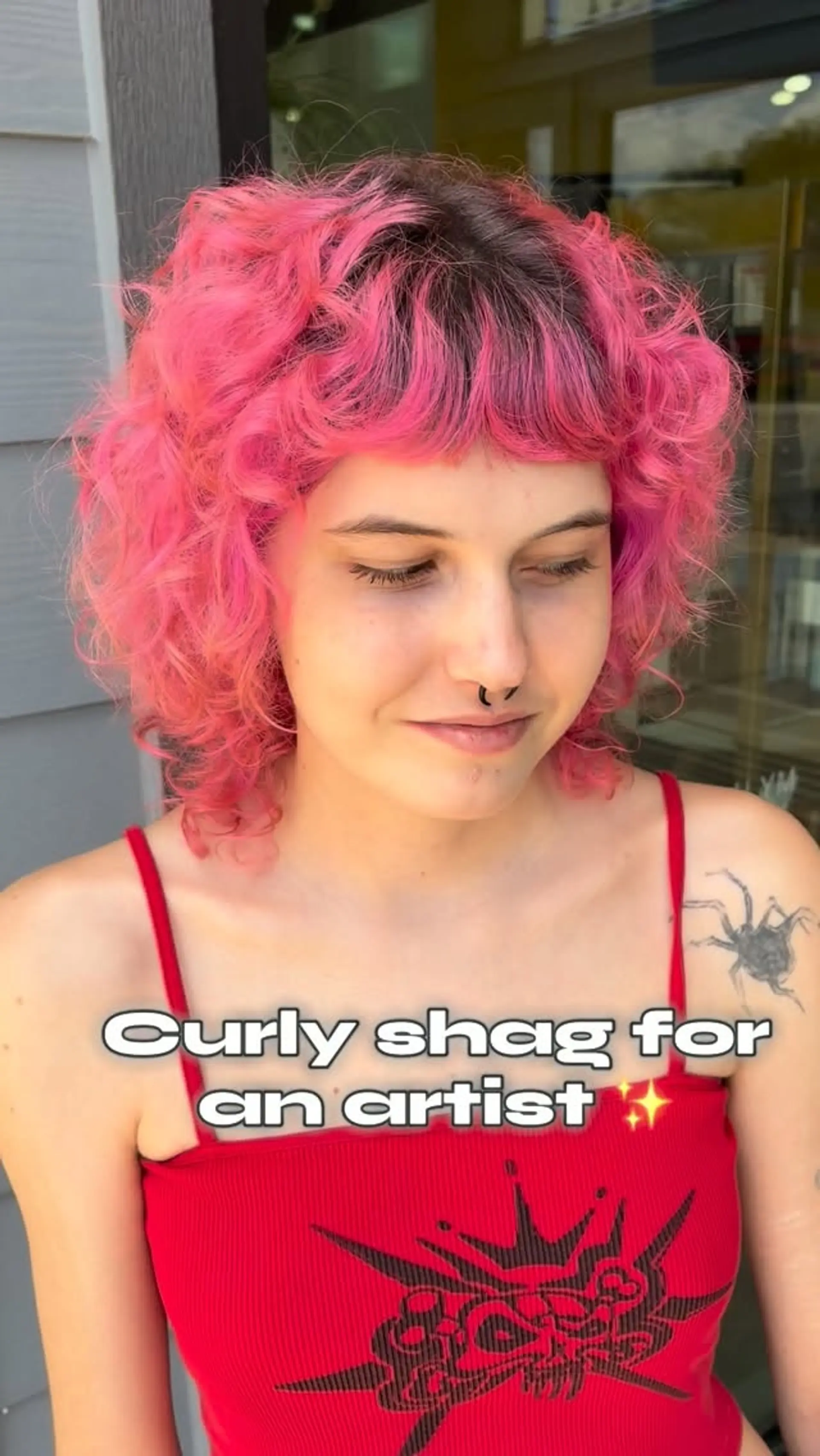 A vibrant bubblegum pink curly shag haircut featuring textured layers, dark natural roots, and short curly fringe bangs. 1