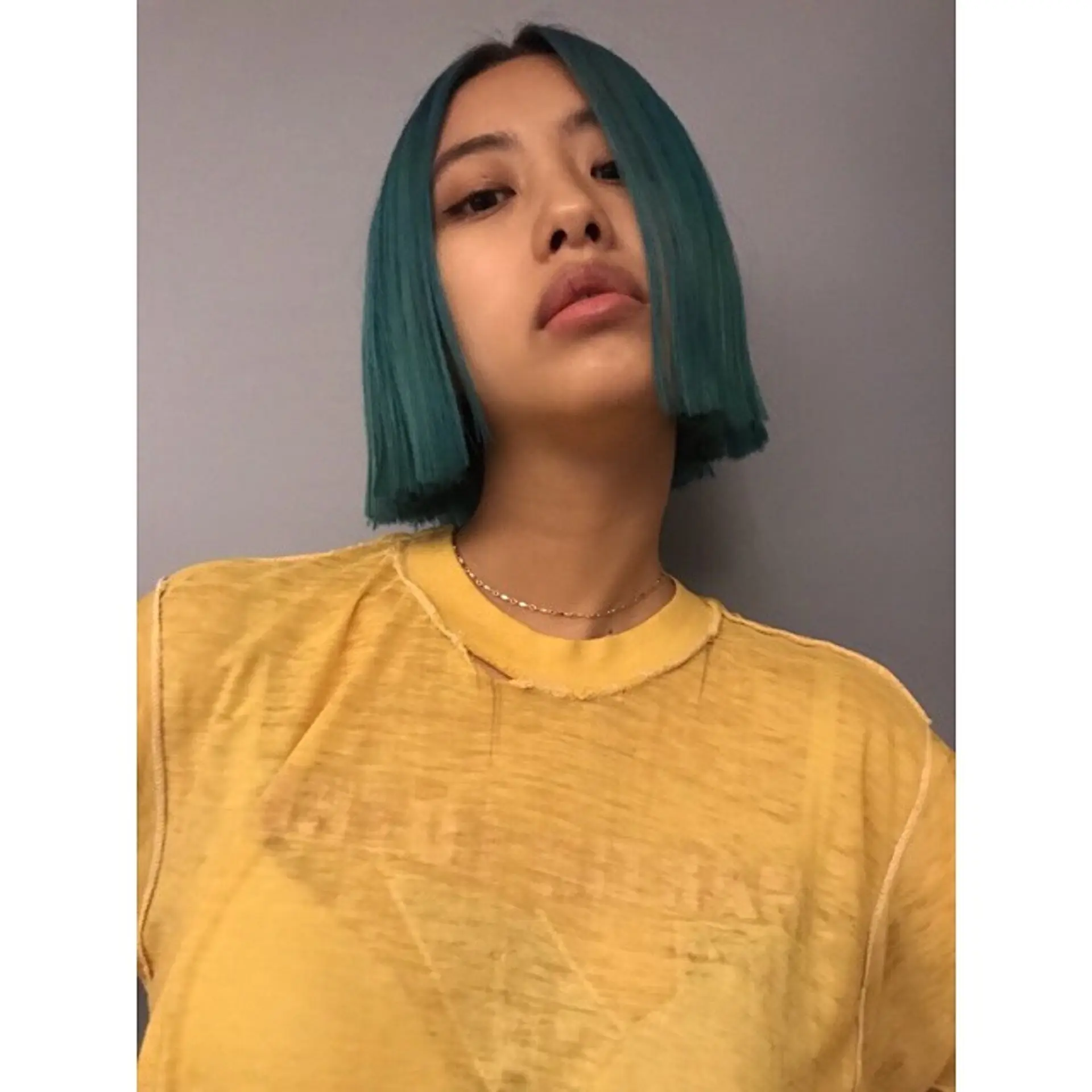 A short, blunt bob haircut with a bold, teal hair color. 1