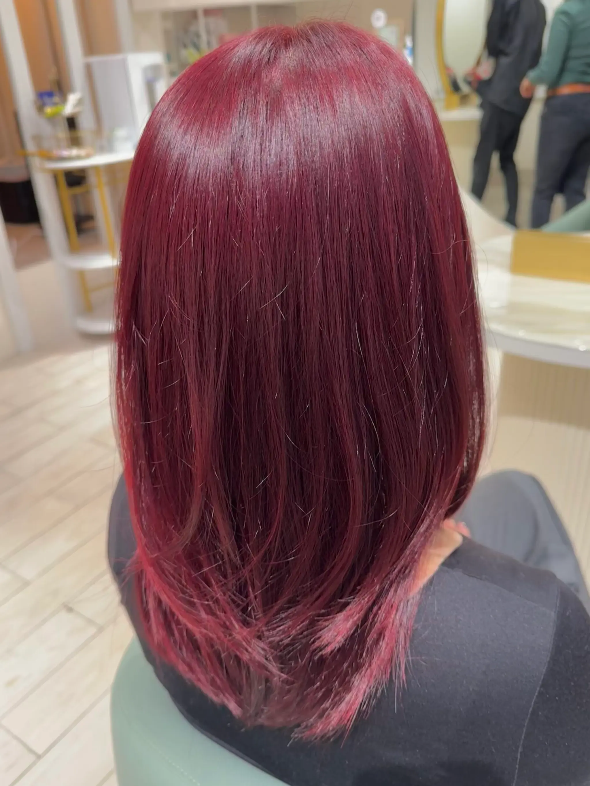 Medium-length, straight, burgundy hair with a radiant shine and layered to create a textured yet sleek appearance.