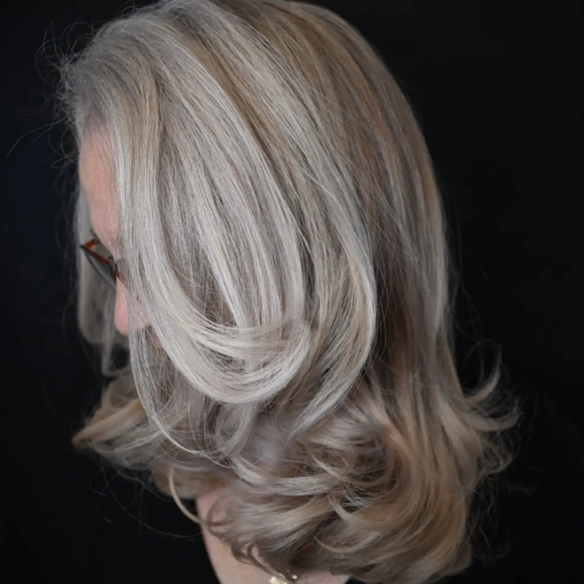 A medium-length silver and ash blonde layered blowout with soft, face-framing curls and smooth finish. 1