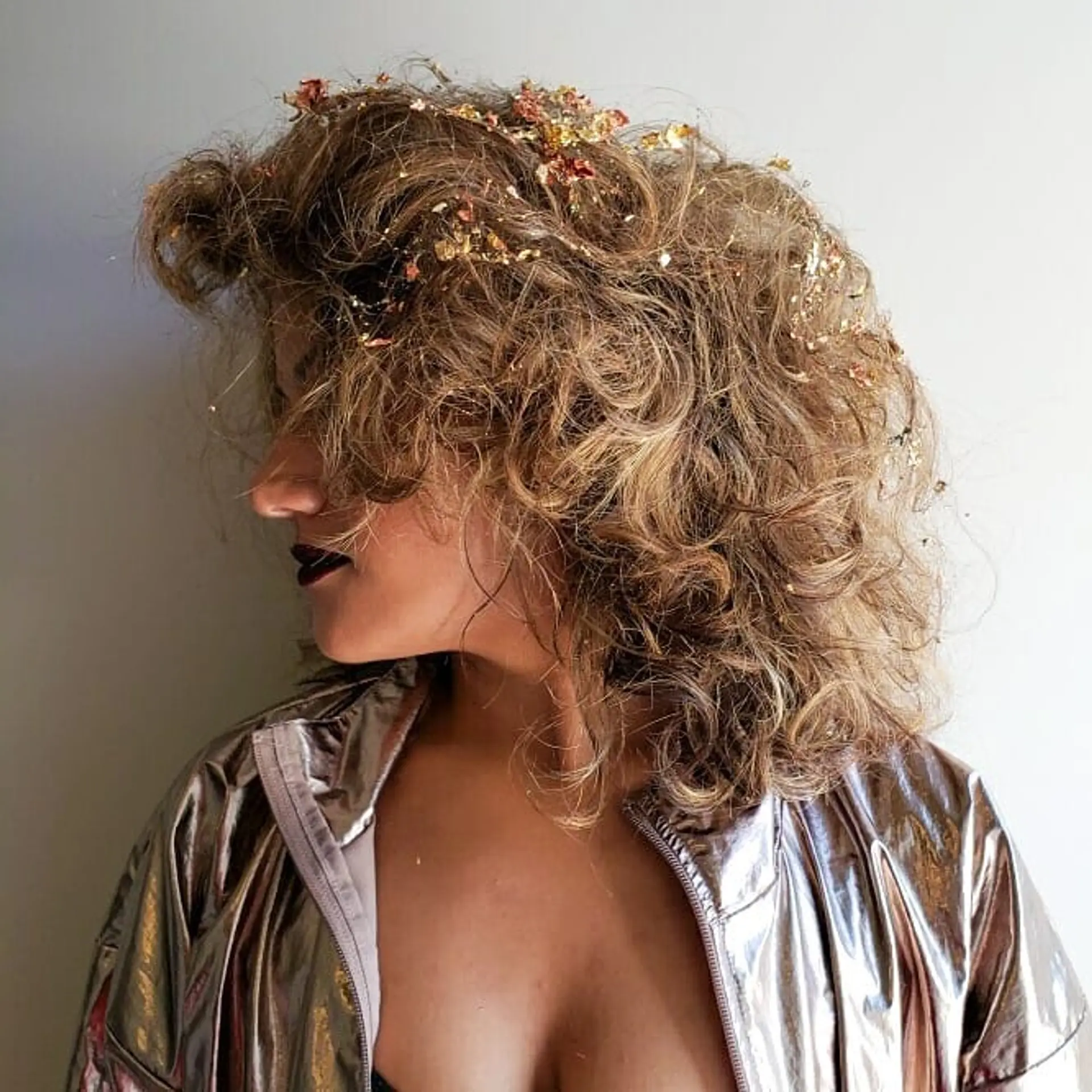 A voluminous, medium-length curly bob with gold leaf accents. The curls are loose and natural, creating a soft and stylish look. 1