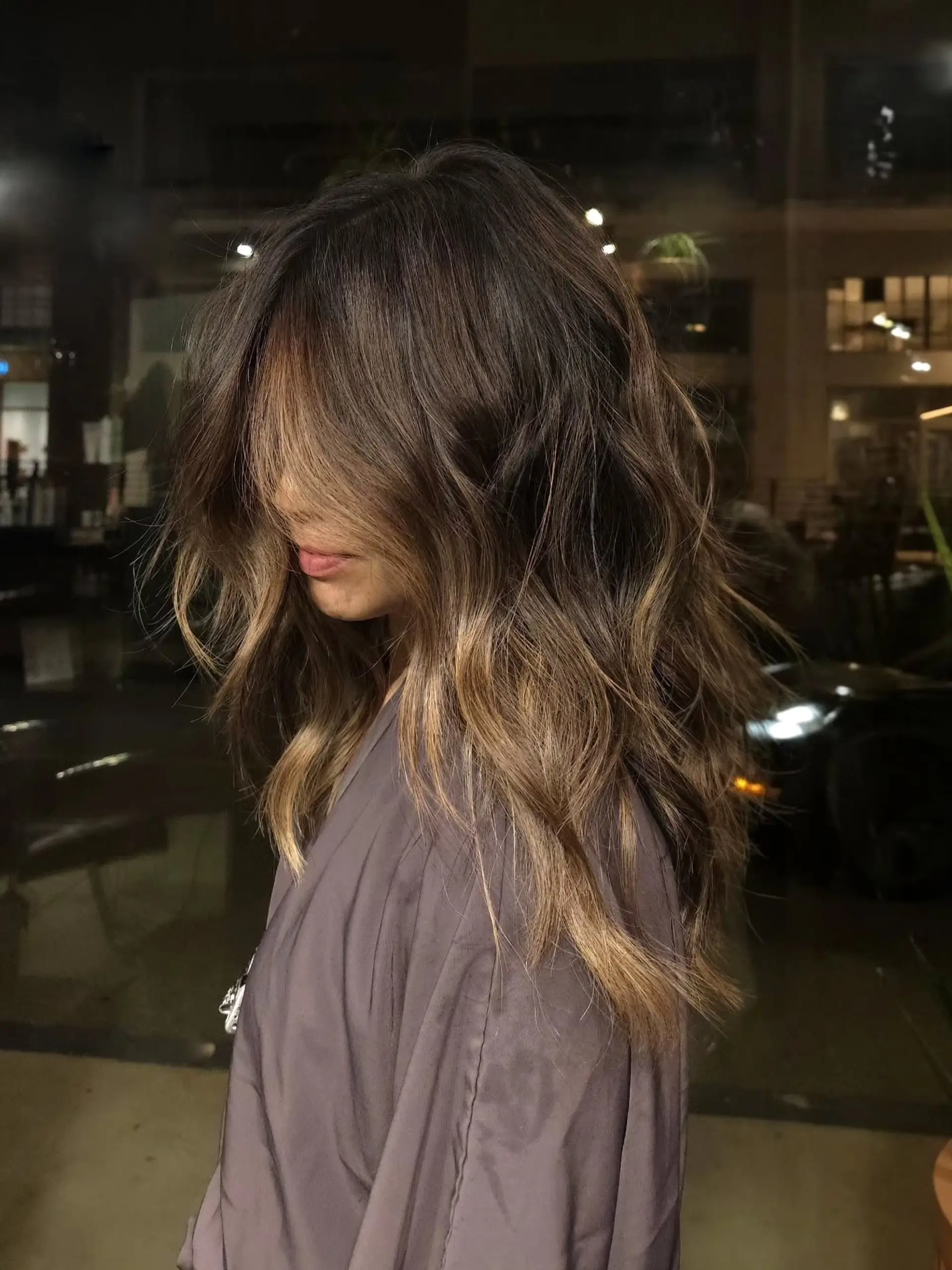 Long layered hair styled in soft, loose waves featuring a seamless bronde balayage blend. 1