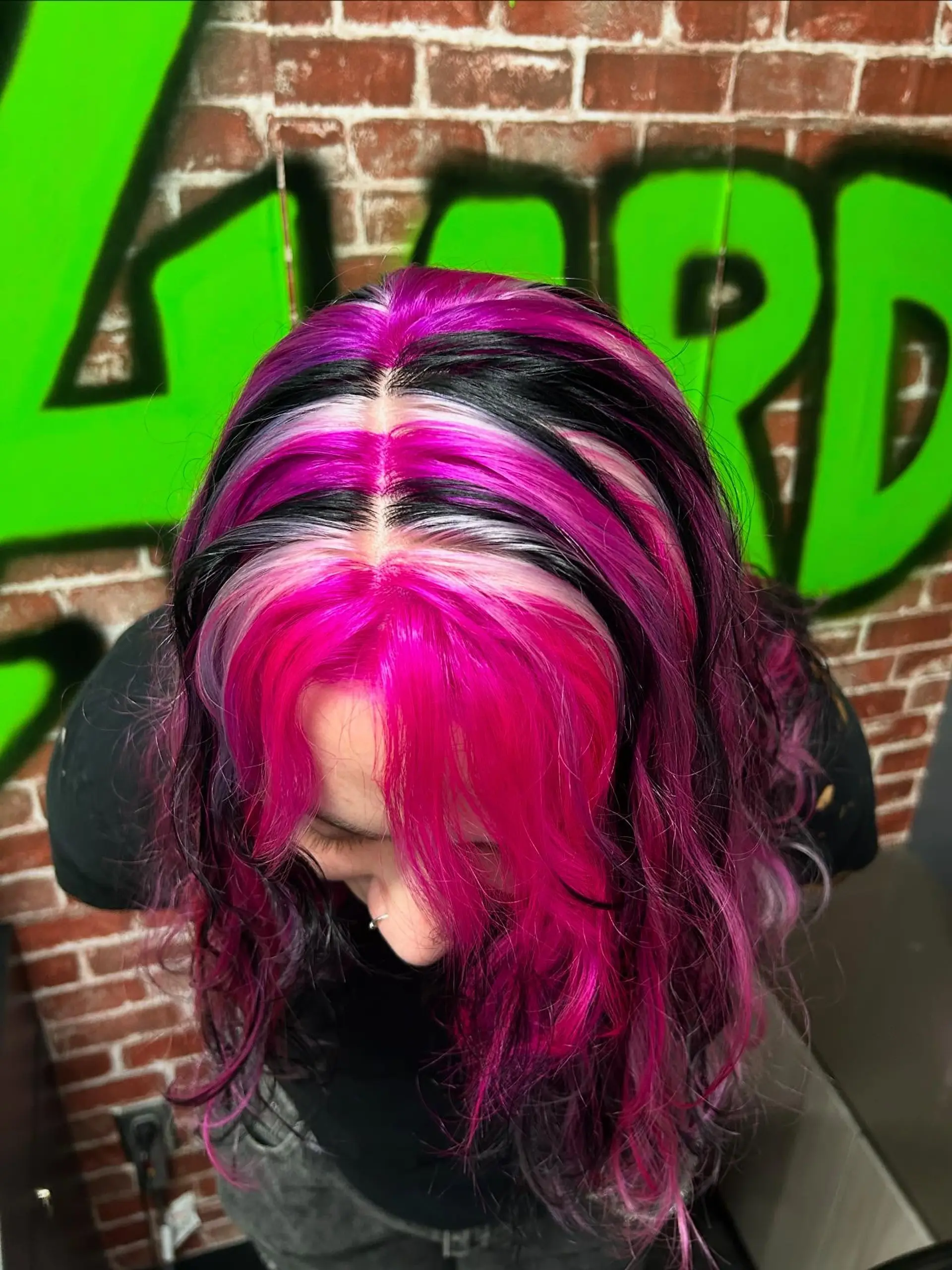 A high-contrast creative color featuring bold, alternating chunky sections of vibrant hot pink, jet black, and icy platinum blonde throughout wavy hair. 1