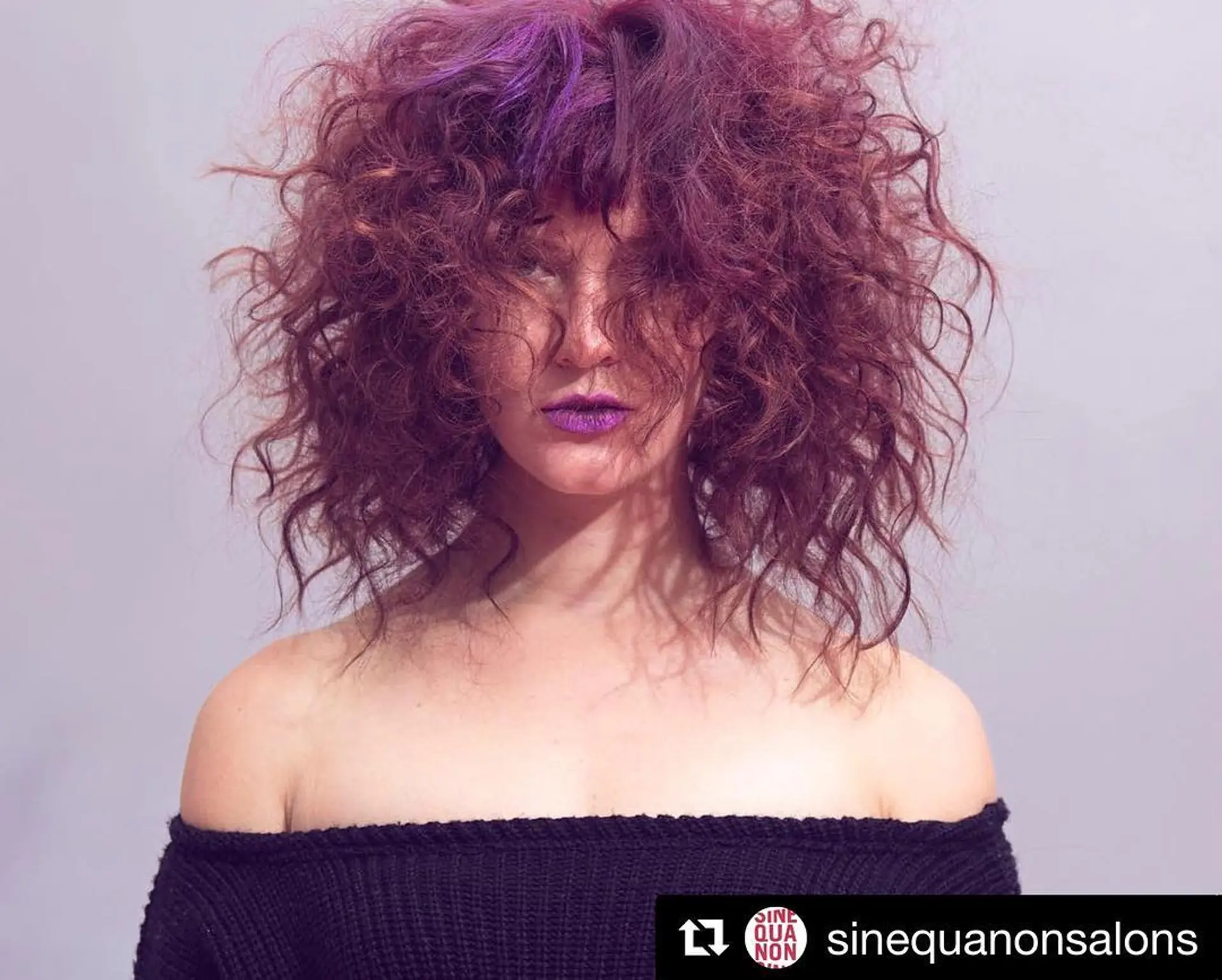 A curly shag haircut with fringe bangs and bold purple and burgundy color. 1