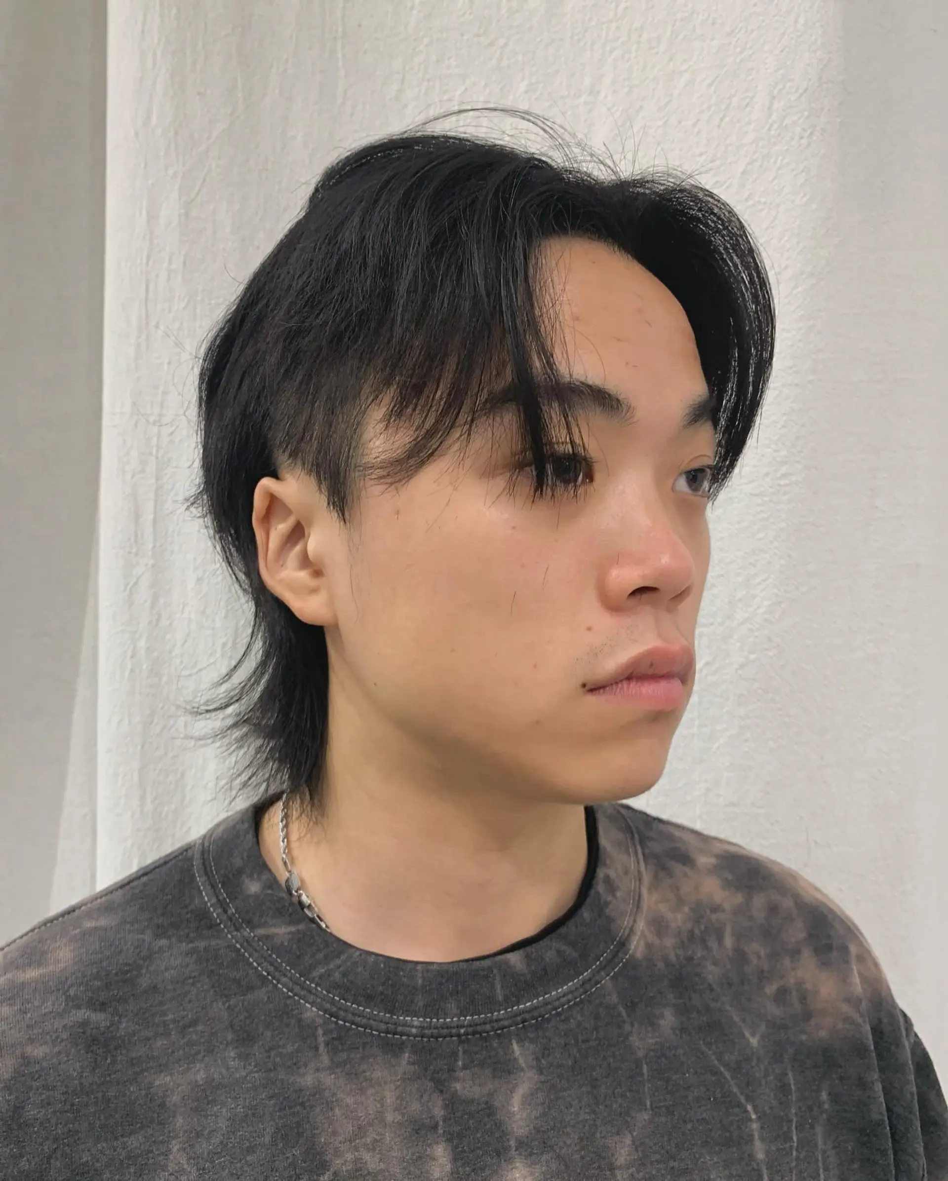 A sleek, medium-length hairstyle with straight black hair, layered bangs, and tapered sides. It combines a relaxed fringe with textured ends for a modern, understated look. 1