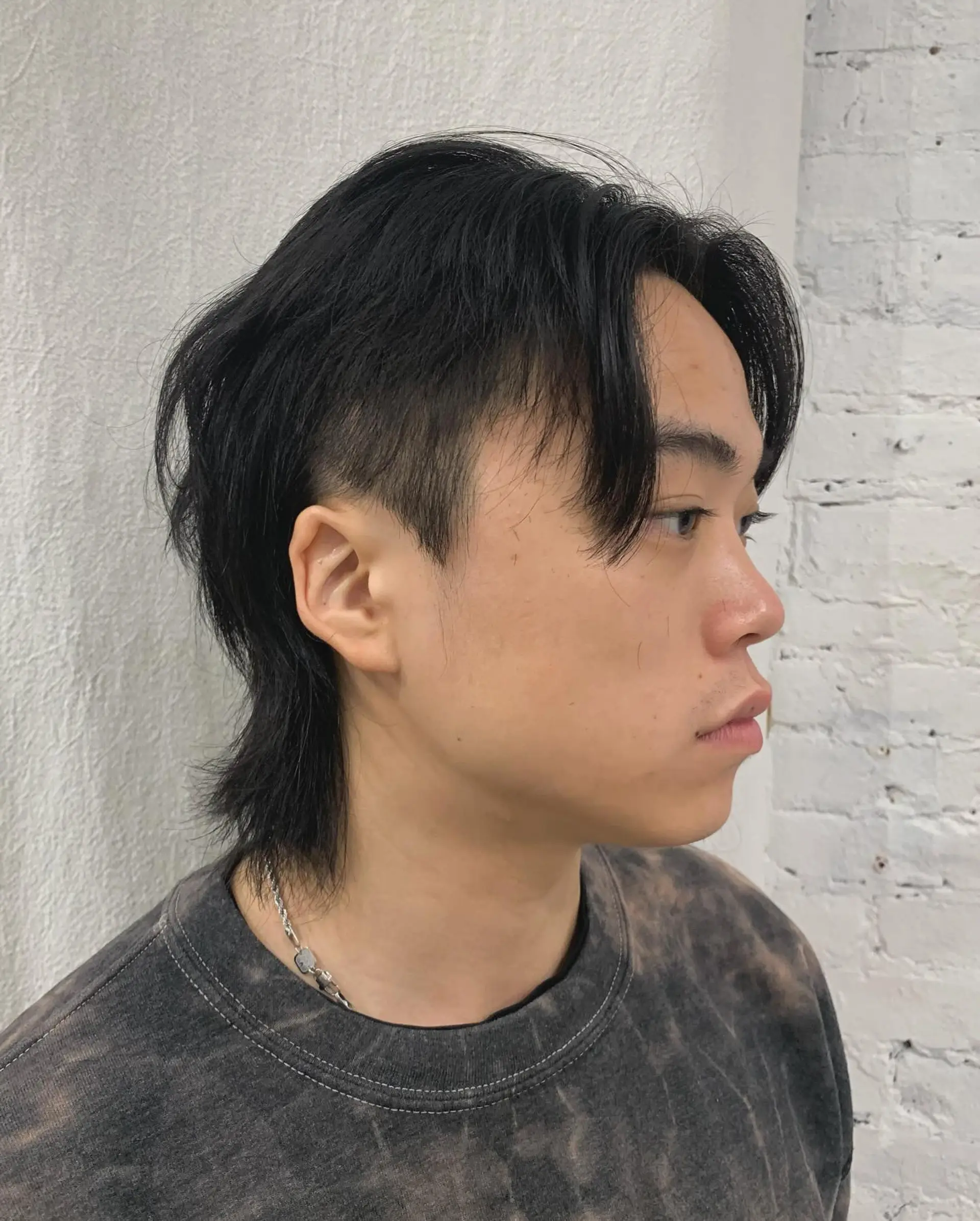 A sleek, medium-length hairstyle with straight black hair, layered bangs, and tapered sides. It combines a relaxed fringe with textured ends for a modern, understated look. 2