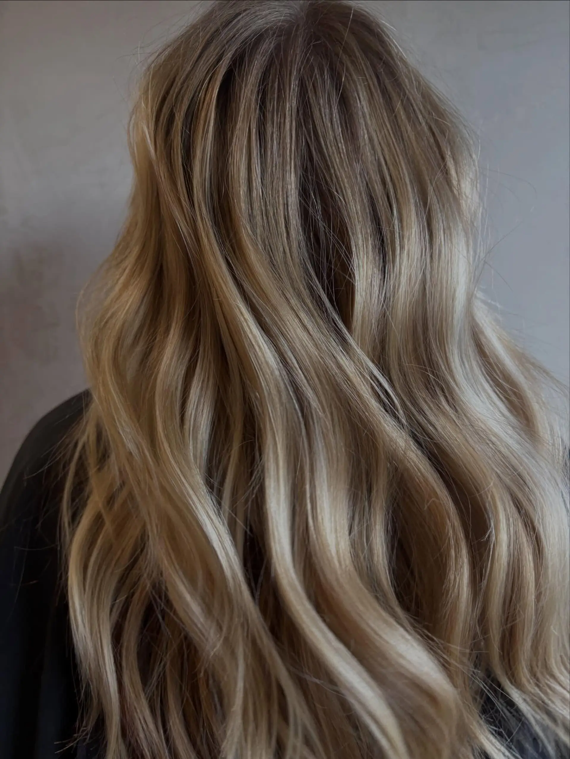 Long, dimensional lived-in blonde hair styled in loose, soft waves with natural root shadowing. 1