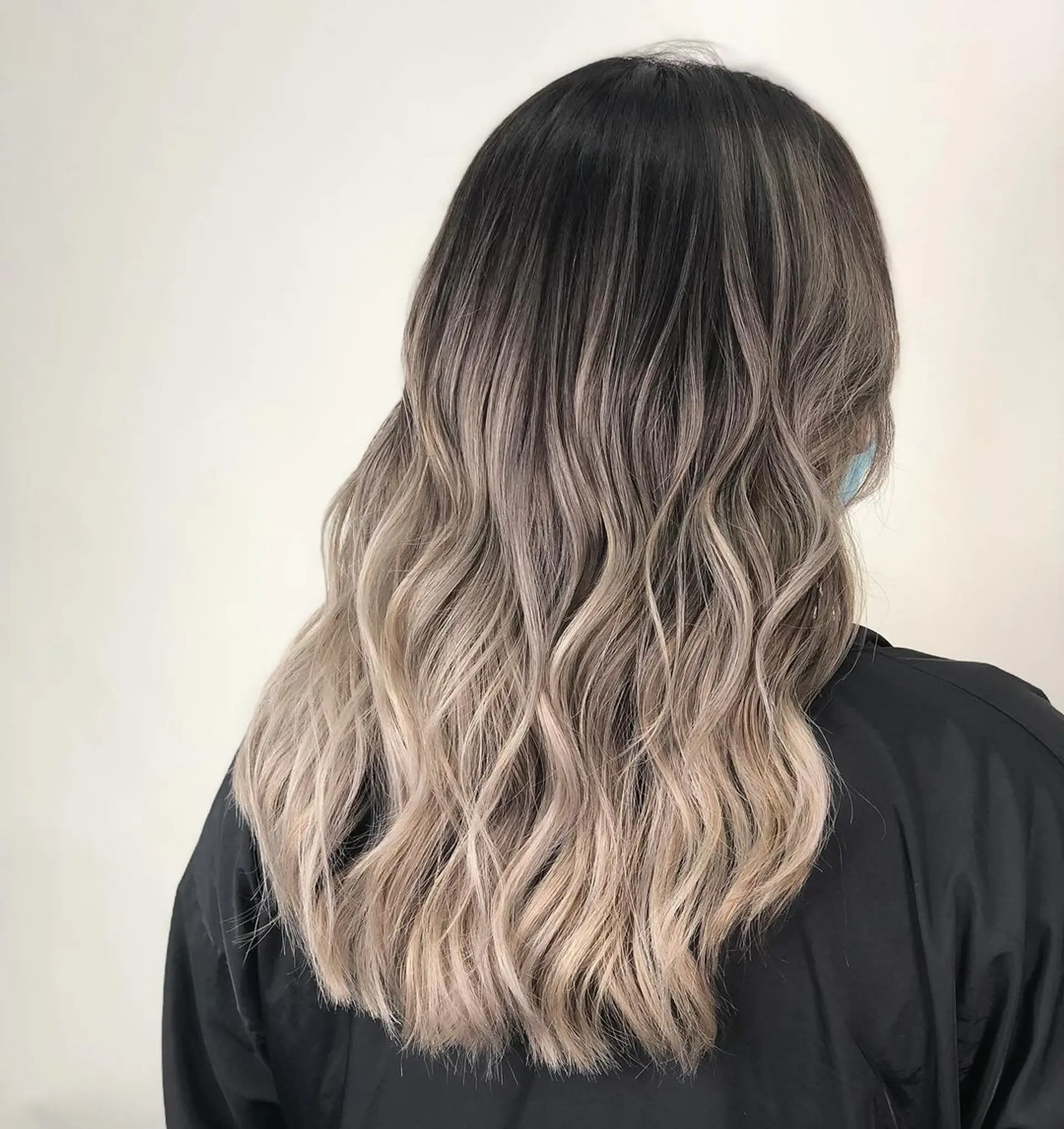 Medium-length, wavy hairstyle featuring an ombre effect transitioning from black roots, to gray, and ending in blonde tips. Soft, loose waves create a flowing, natural look.
Stylist - @xcellent_jason 1