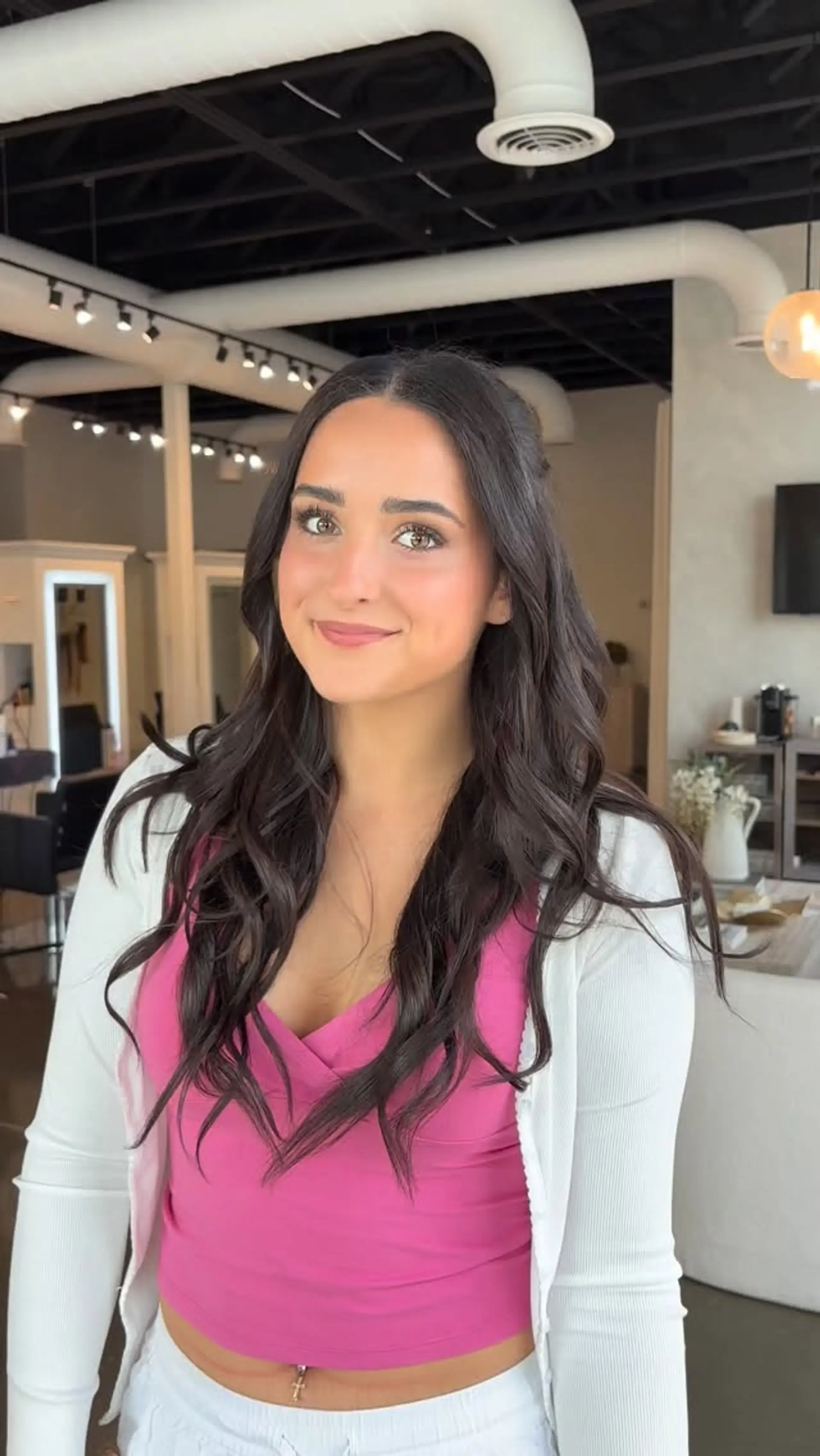 Long dark brunette hair styled with soft, loose waves and a clean center part. 1