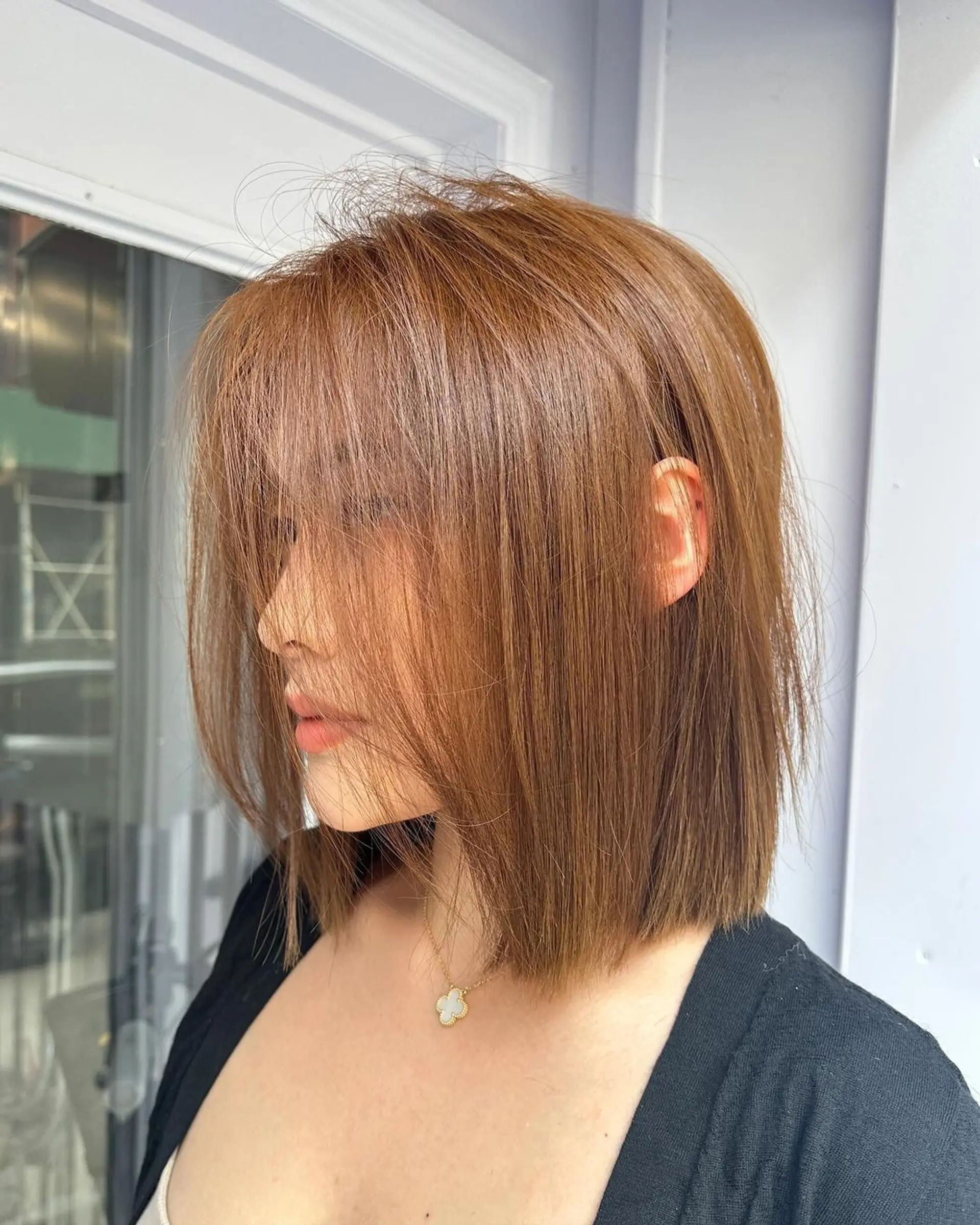 A light brown and copper medium-length hairstyle featuring straight, blunt ends with subtle layers and side-swept bangs for a sleek and sophisticated look. 1