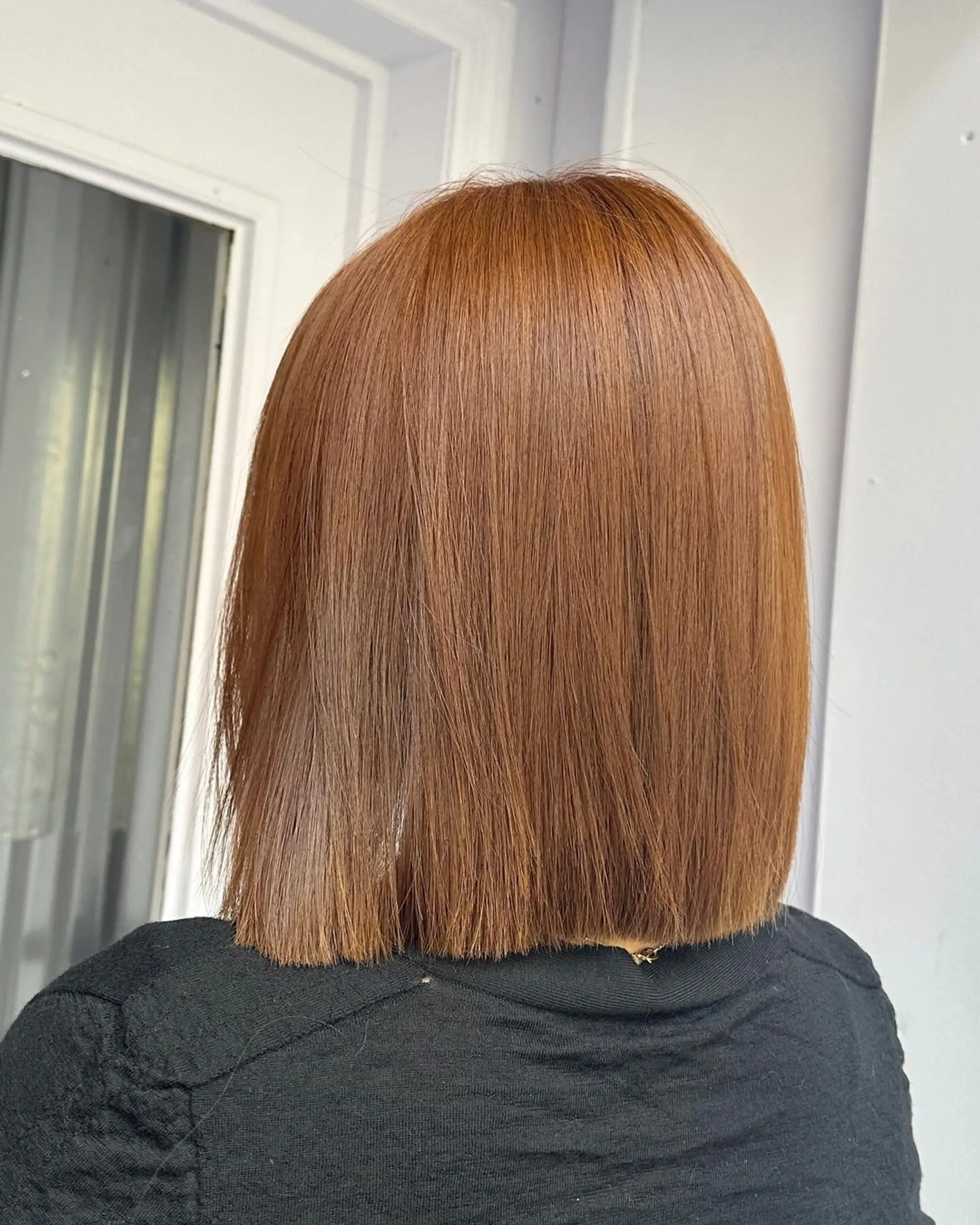 A light brown and copper medium-length hairstyle featuring straight, blunt ends with subtle layers and side-swept bangs for a sleek and sophisticated look. 2
