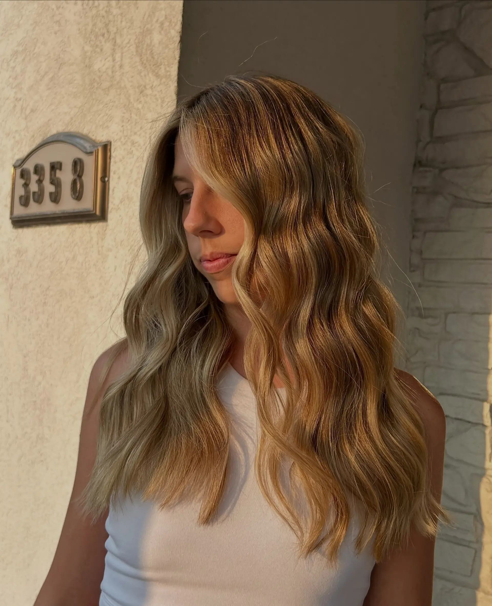 Long hair featuring a warm golden balayage styled in soft textured waves. 1