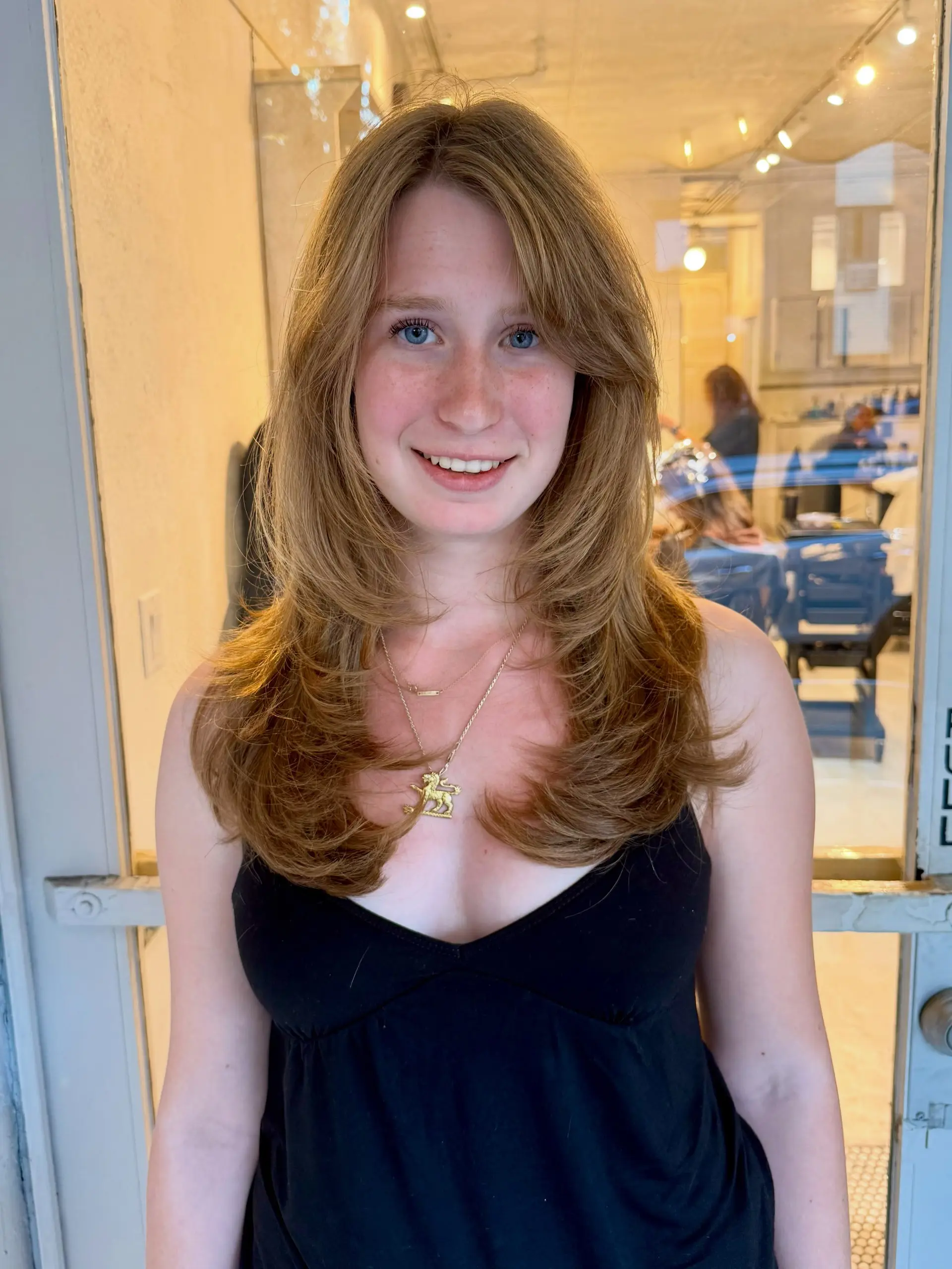 A long, feathered layered haircut styled into a soft, voluminous blowout with face-framing curtain bangs curving gently inward. 1