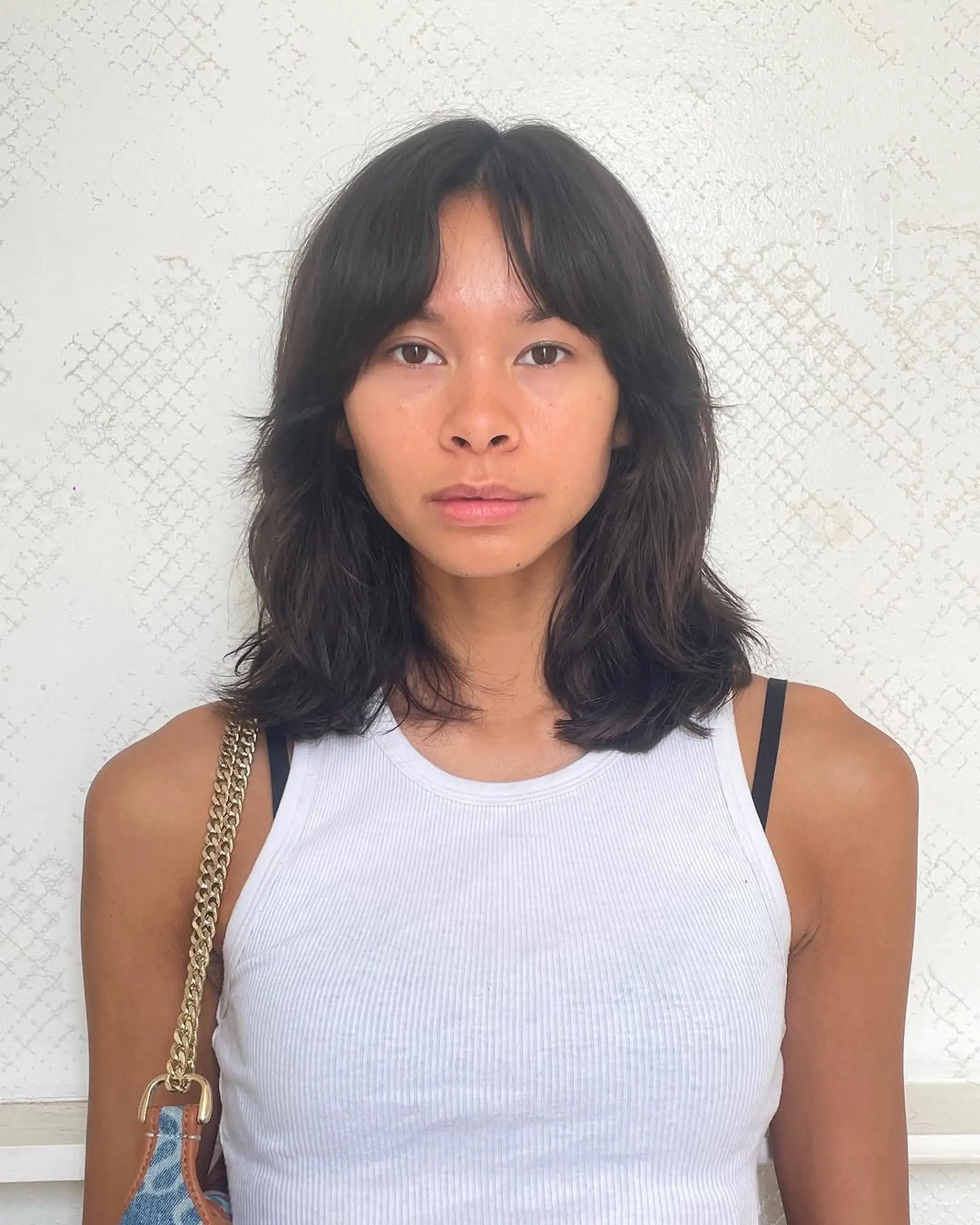 A casual medium-length cut with natural waves, soft layers, and curtain bangs, creating a modern and laid-back style. 1