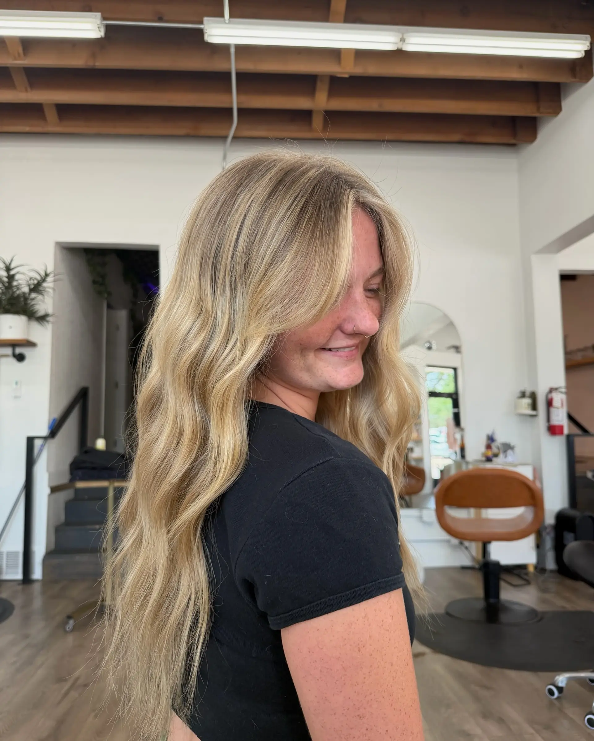 Long, flowing warm blonde hair styled in soft, loose waves with face-framing curtain bangs. 1