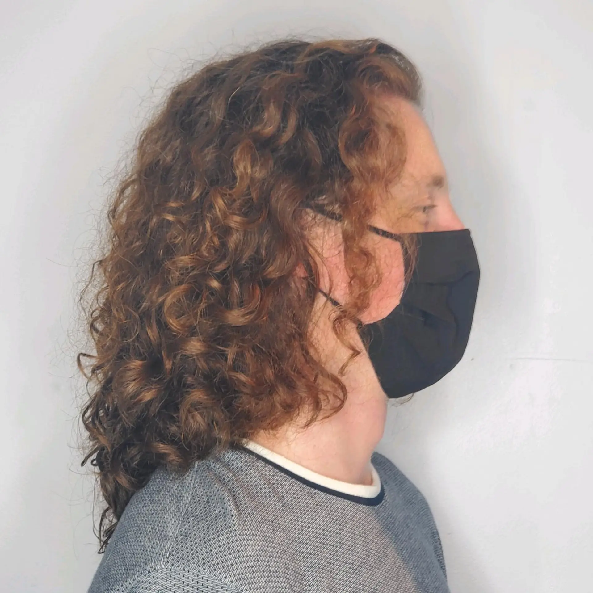 Shoulder-length layered cut styled with well-defined, natural bouncy curls in warm auburn-brown tones. 1
