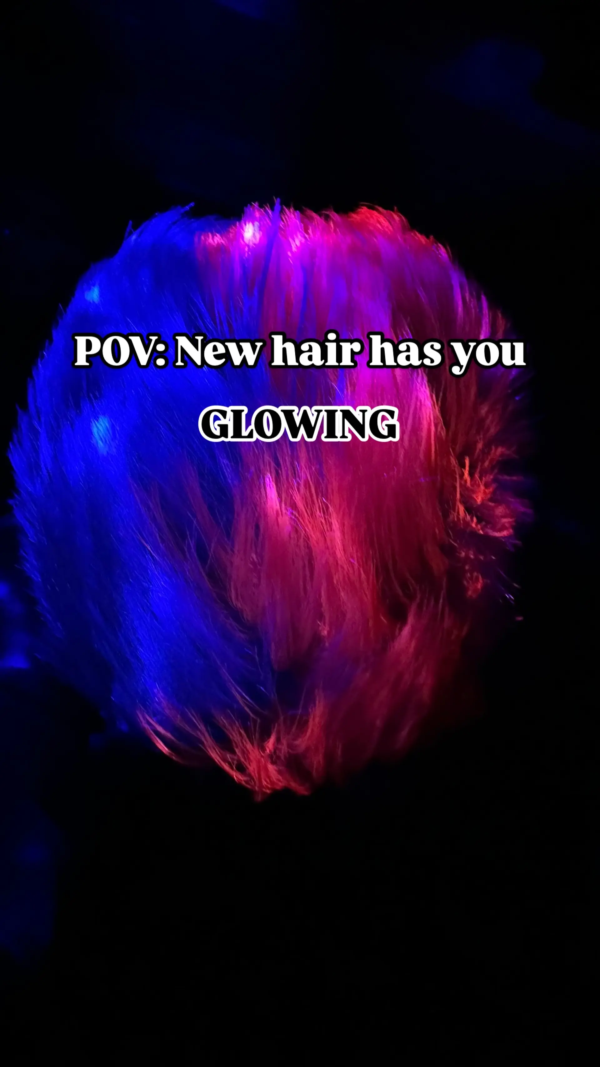 A bold split-tone short pixie cut illuminated under blacklight with vivid neon blue on one side and electric pink on the other. 1
