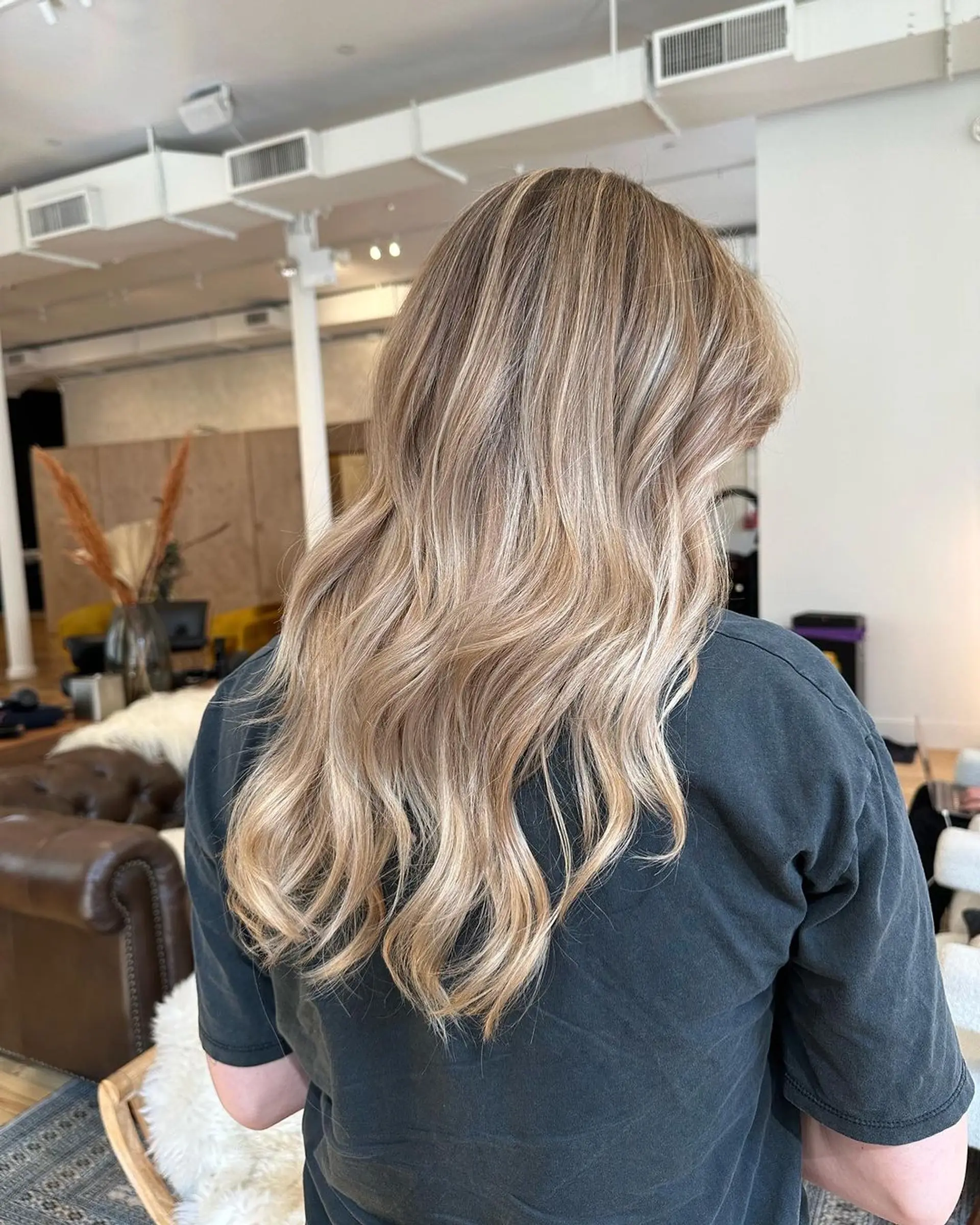 This long, wavy hairstyle features a beautiful blend of blonde and golden hues, giving it a sun-kissed appearance. The waves cascade naturally down the shoulders, creating a relaxed and effortless look. 1