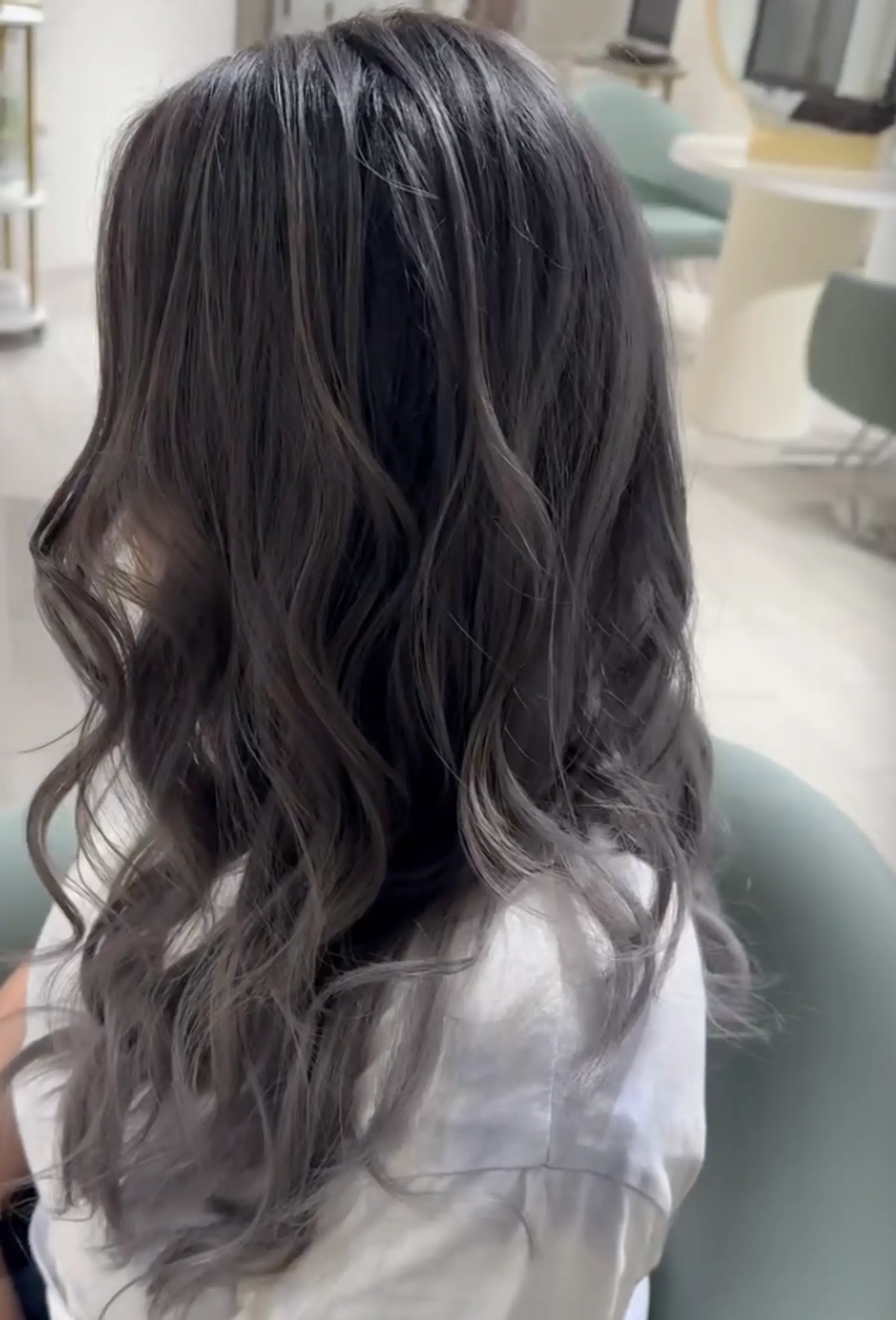Long, wavy hair in ash gray and silver ombre with soft, loose curls and a layered cut.

Stylist: @yurihair.newyork 3
