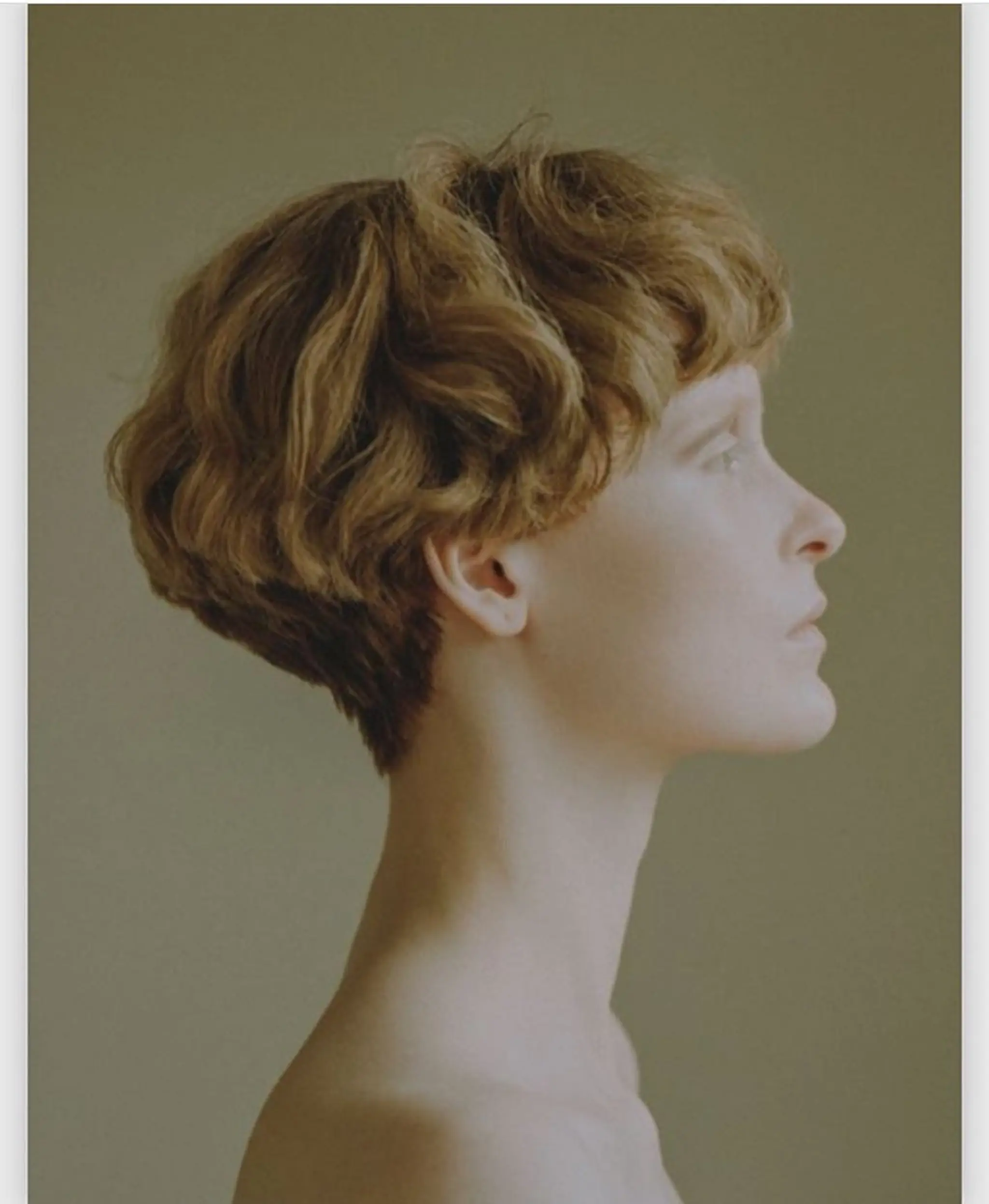 Short wavy hairstyle with golden blonde color, featuring volume at the crown and a tapered nape with soft, layered waves.