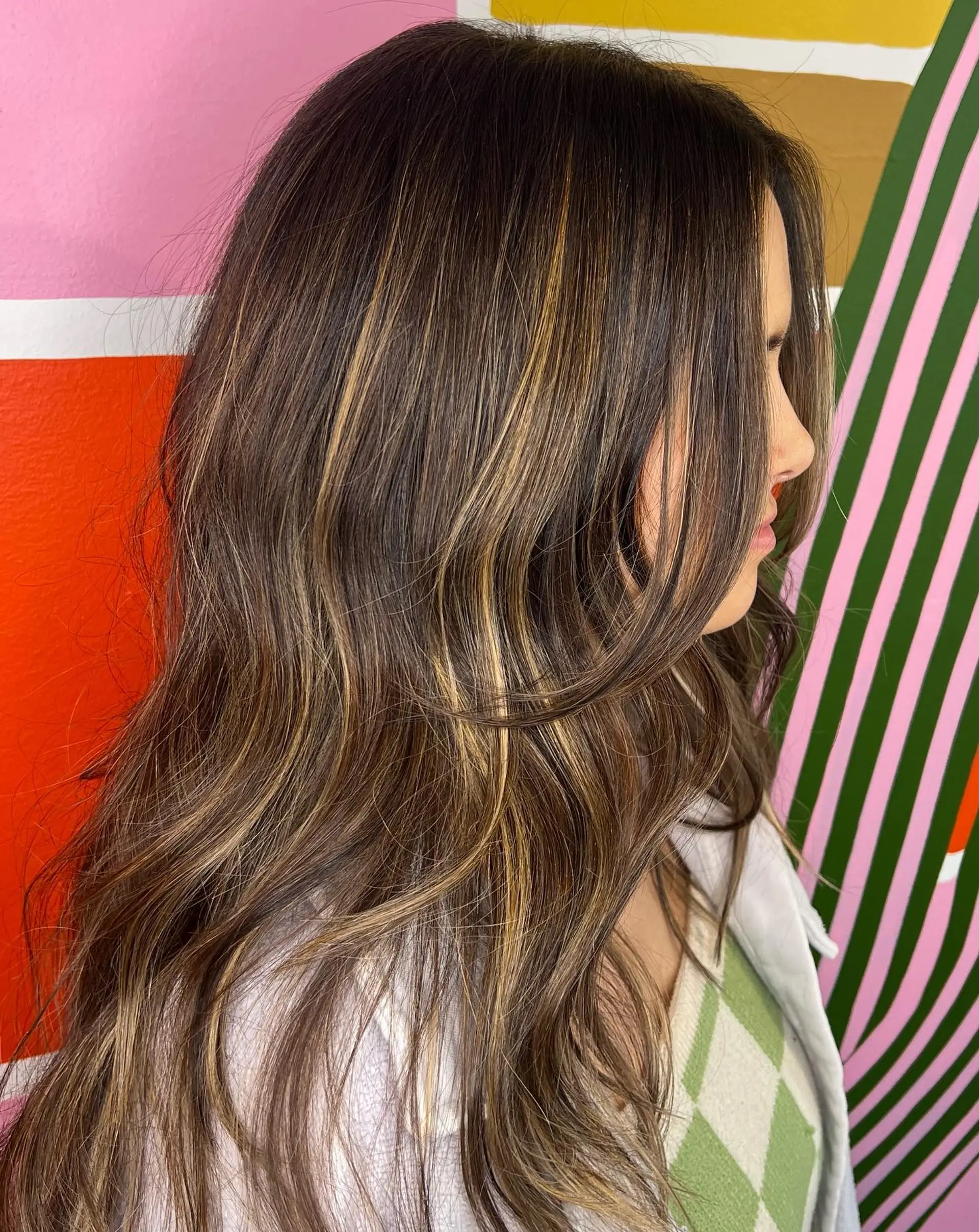 Long dark brown hair styled in soft waves with dimensional caramel balayage highlights and face-framing layers. 1