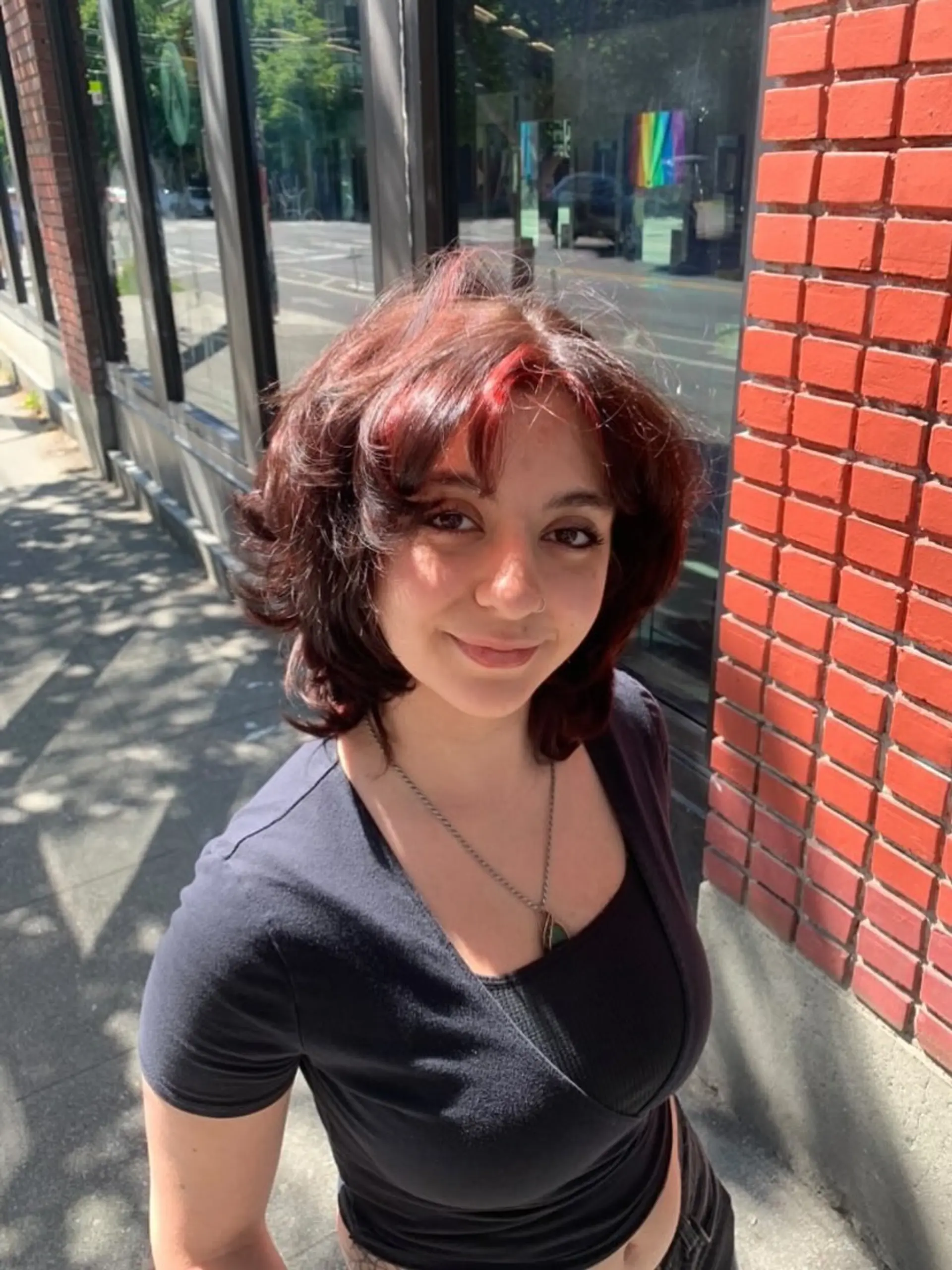 A voluminous, textured shag haircut featuring face-framing curtain bangs and bold red highlights contrasting with deep auburn-brown hair. 1