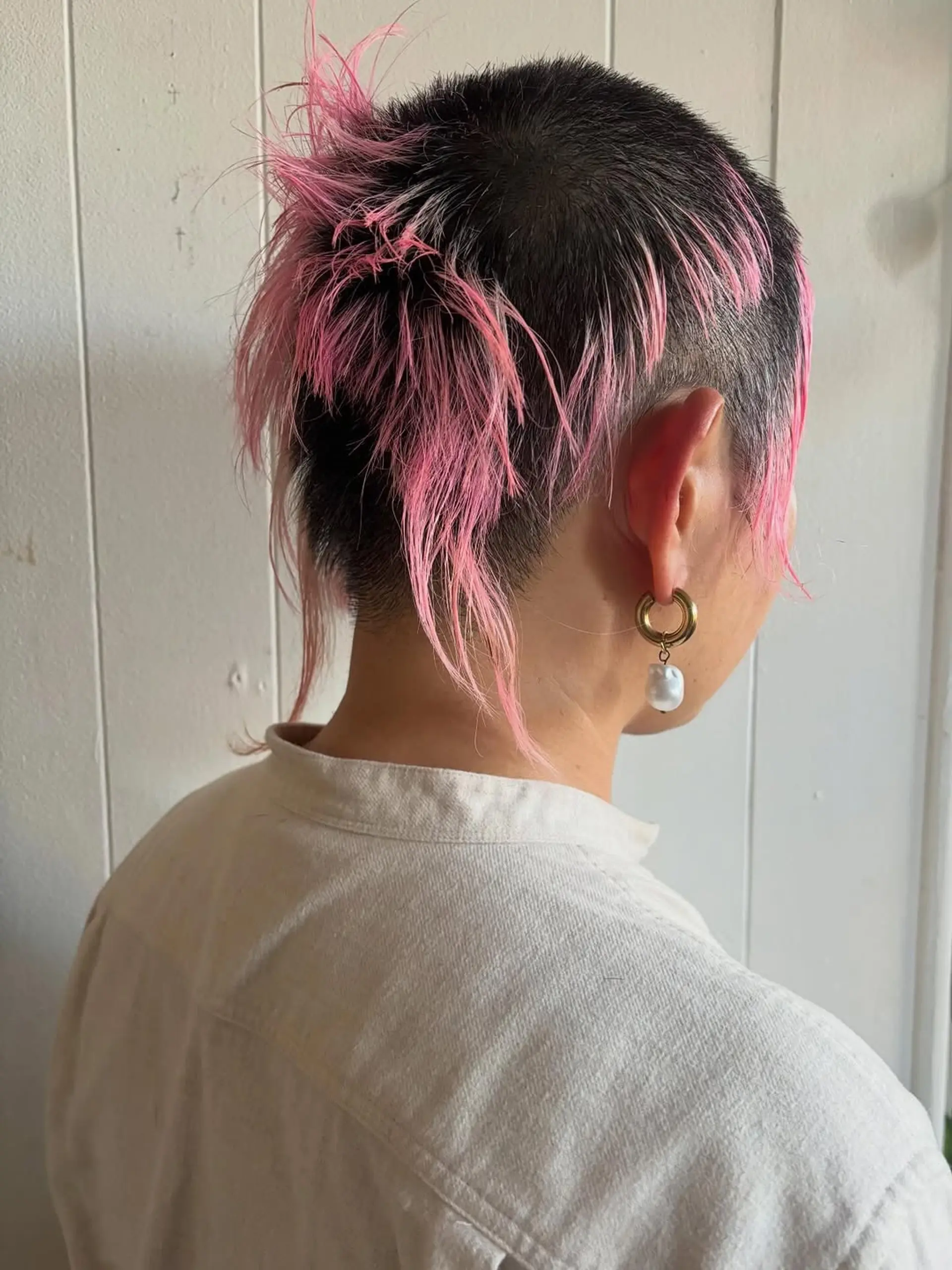 A disconnected, layered pixie-mullet hybrid with shaved sides and long, piecey, vibrant pink ends. 1