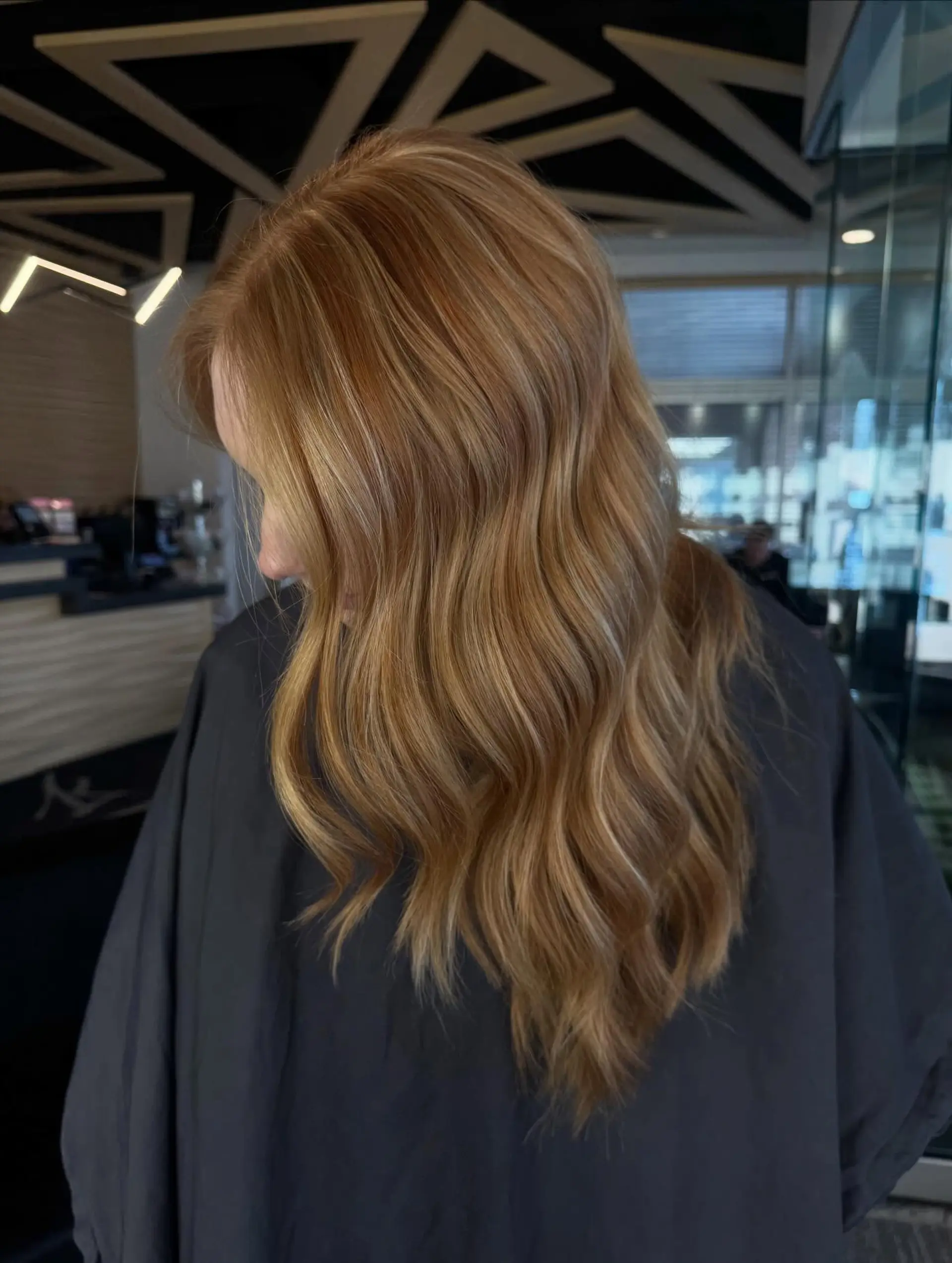 Long warm copper hair enhanced with fine golden highlights and styled into soft, flowing waves. 1