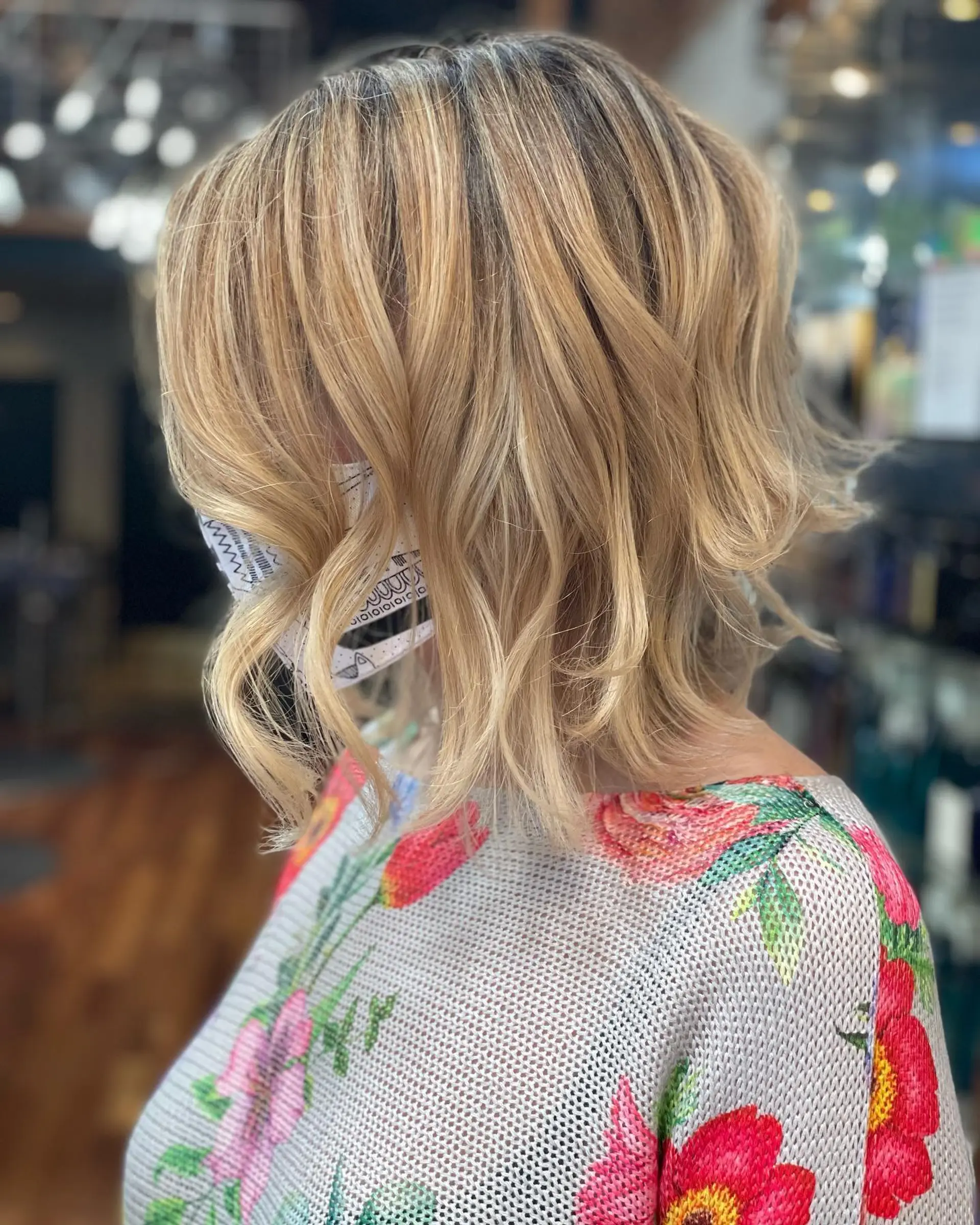 A textured shoulder-length bob cut styled in loose, beachy waves with dimensional blonde highlights. 1