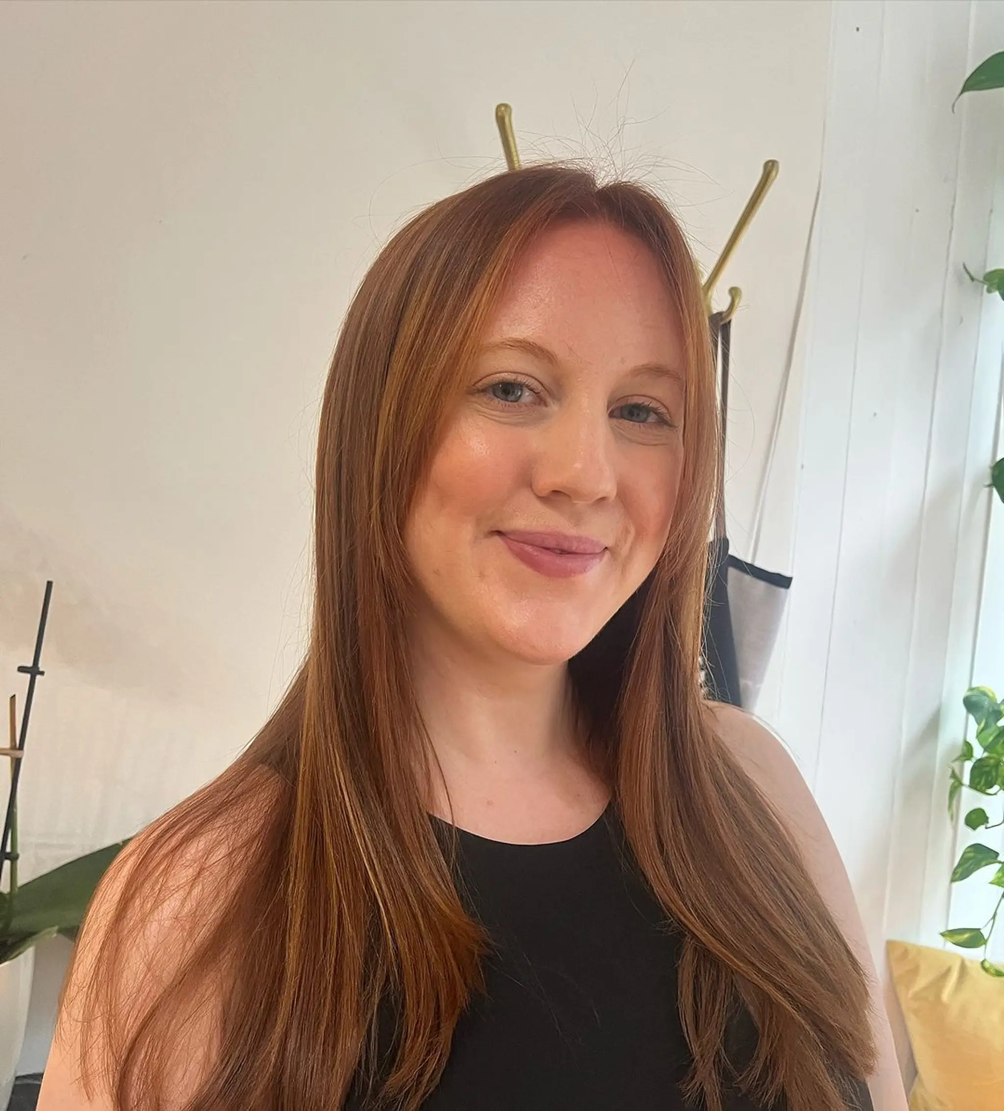 The 'Sunset Glide' hairstyle features medium-length, straight hair that flows gracefully past the shoulders. The hair is parted in the middle, with smooth, silky strands that frame the face elegantly. The rich hues of red and auburn add a natural sheen and warmth to the overall look.