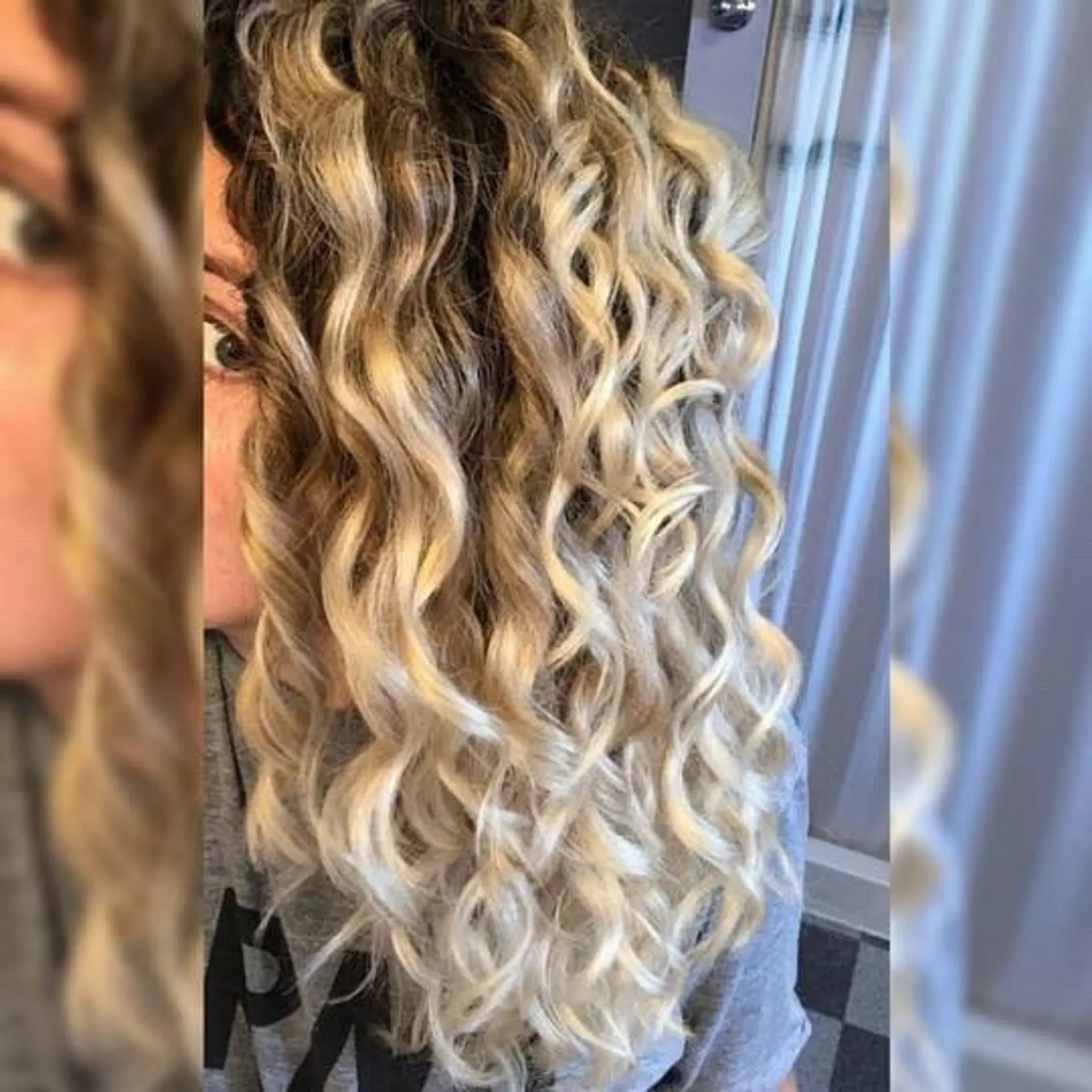 Defined spiral curls enhanced with a seamless blonde balayage and natural rooted depth. 1