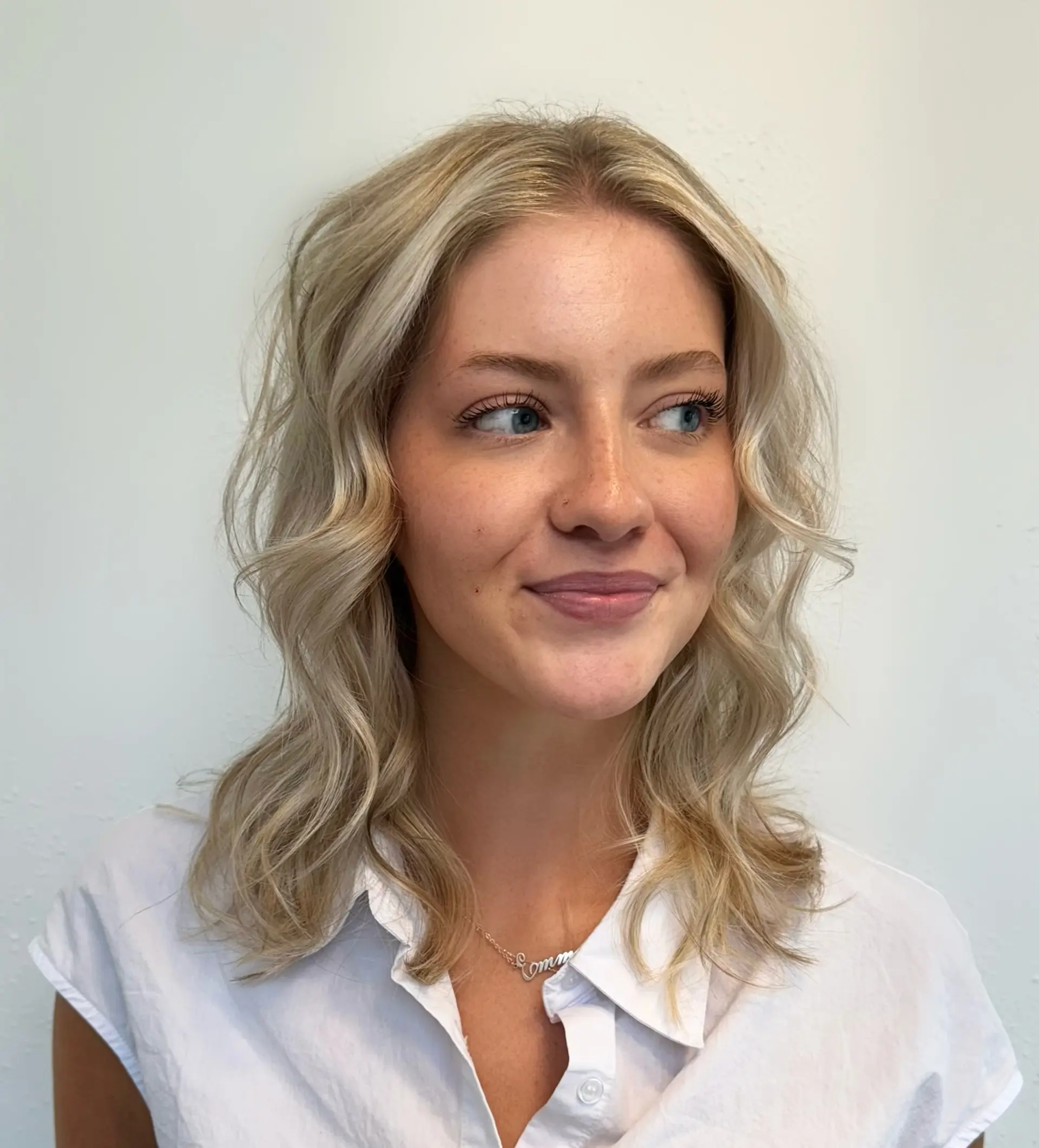 Shoulder-length dimensional light blonde hair styled into soft, beachy waves with textured face-framing layers. 1