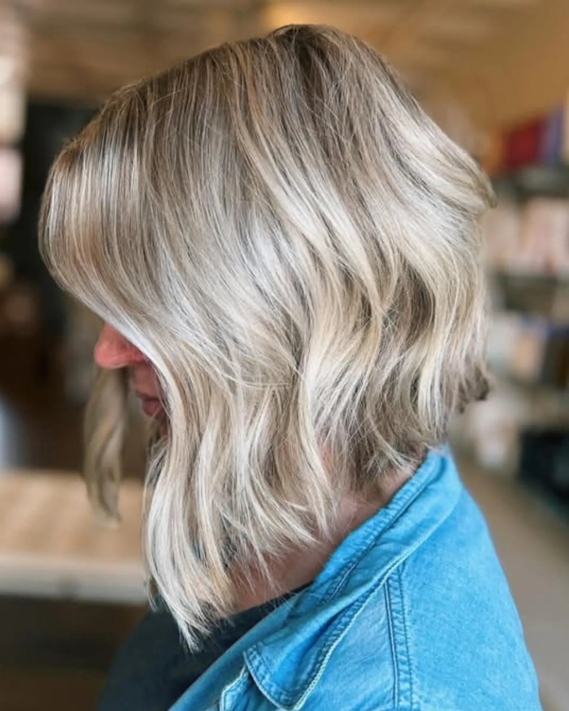 A textured, angled A-line bob styled with soft, undone waves and bright dimensional ash-blonde highlights. 1