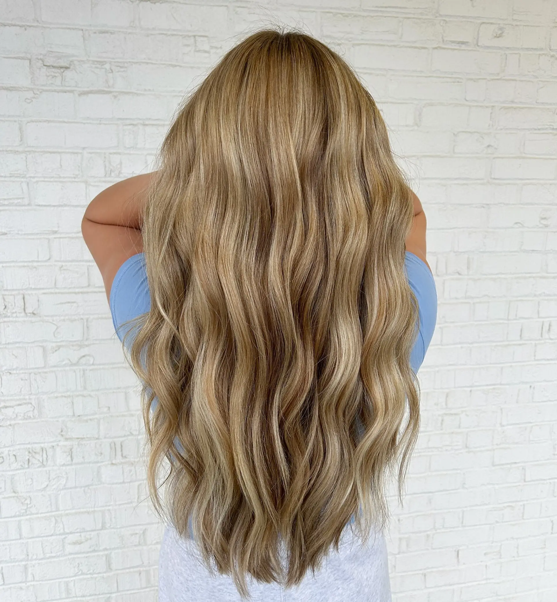 Long honey blonde hair styled in soft, cascading waves. 1